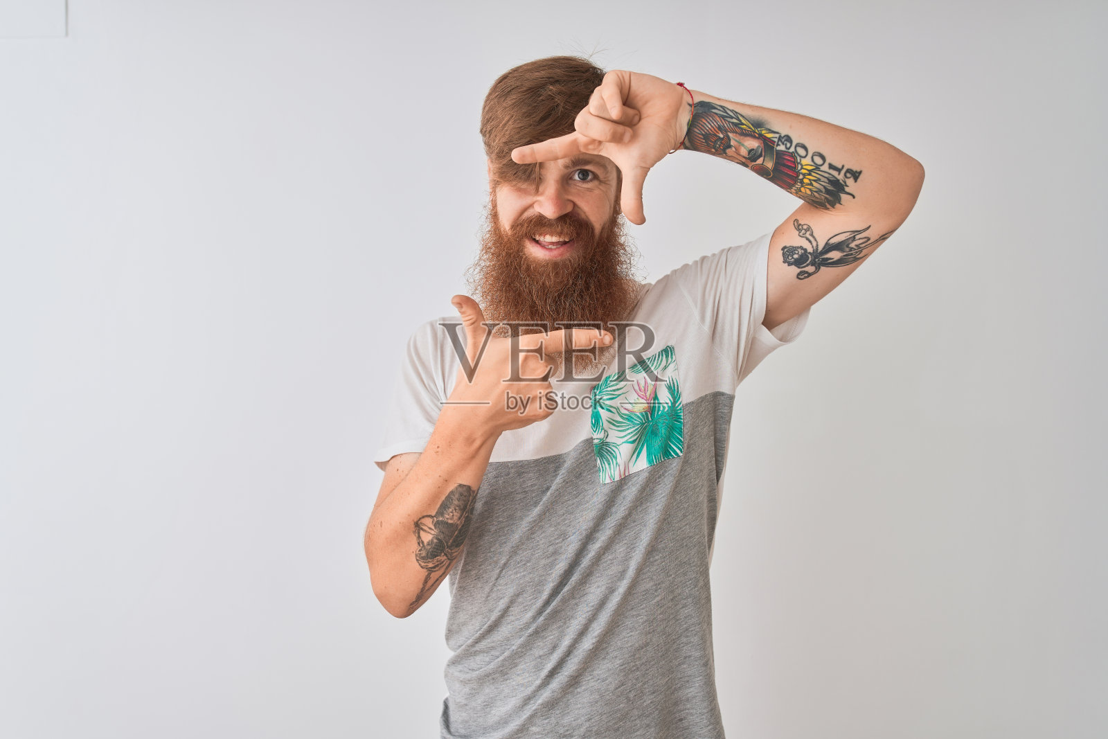 年轻的红发爱尔兰男子穿着t恤站在孤立的白色背景微笑，使框架与手和手指与幸福的脸。创意和摄影概念。照片摄影图片