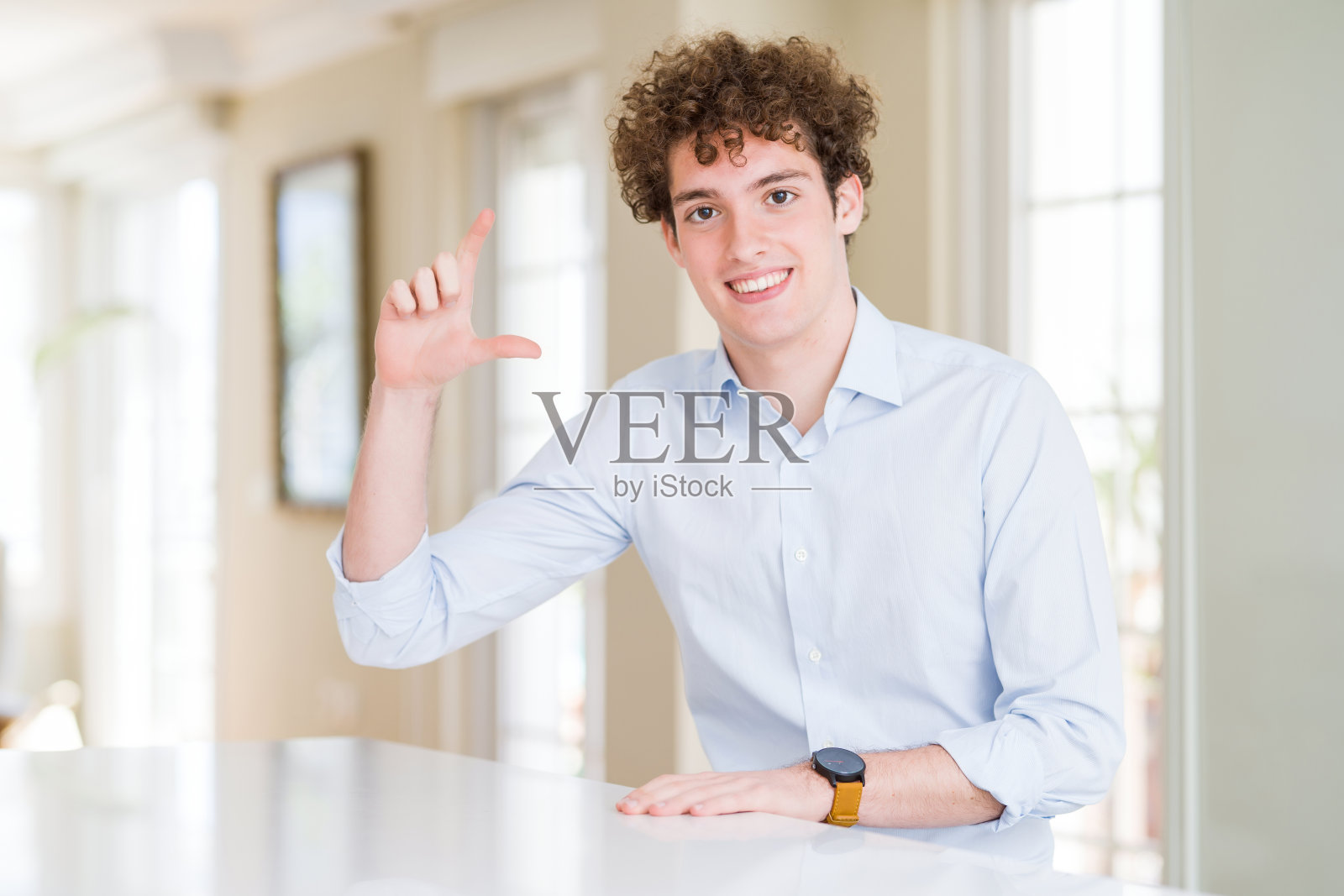 年轻的商人与卷曲读头微笑和自信的手势与手做小尺寸的标志，手指看和相机。测量的概念。照片摄影图片