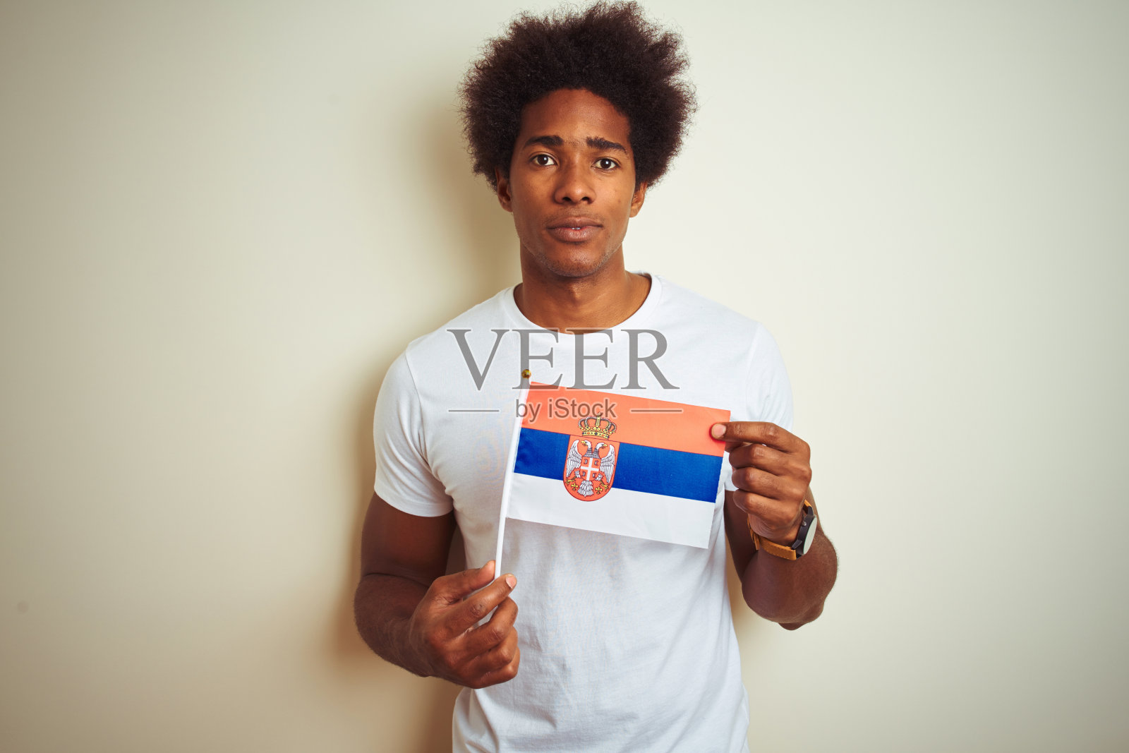 年轻的美国黑人男子举着塞尔维亚塞尔维亚国旗站在孤立的白色背景与自信的表情在聪明的脸上思考严肃照片摄影图片