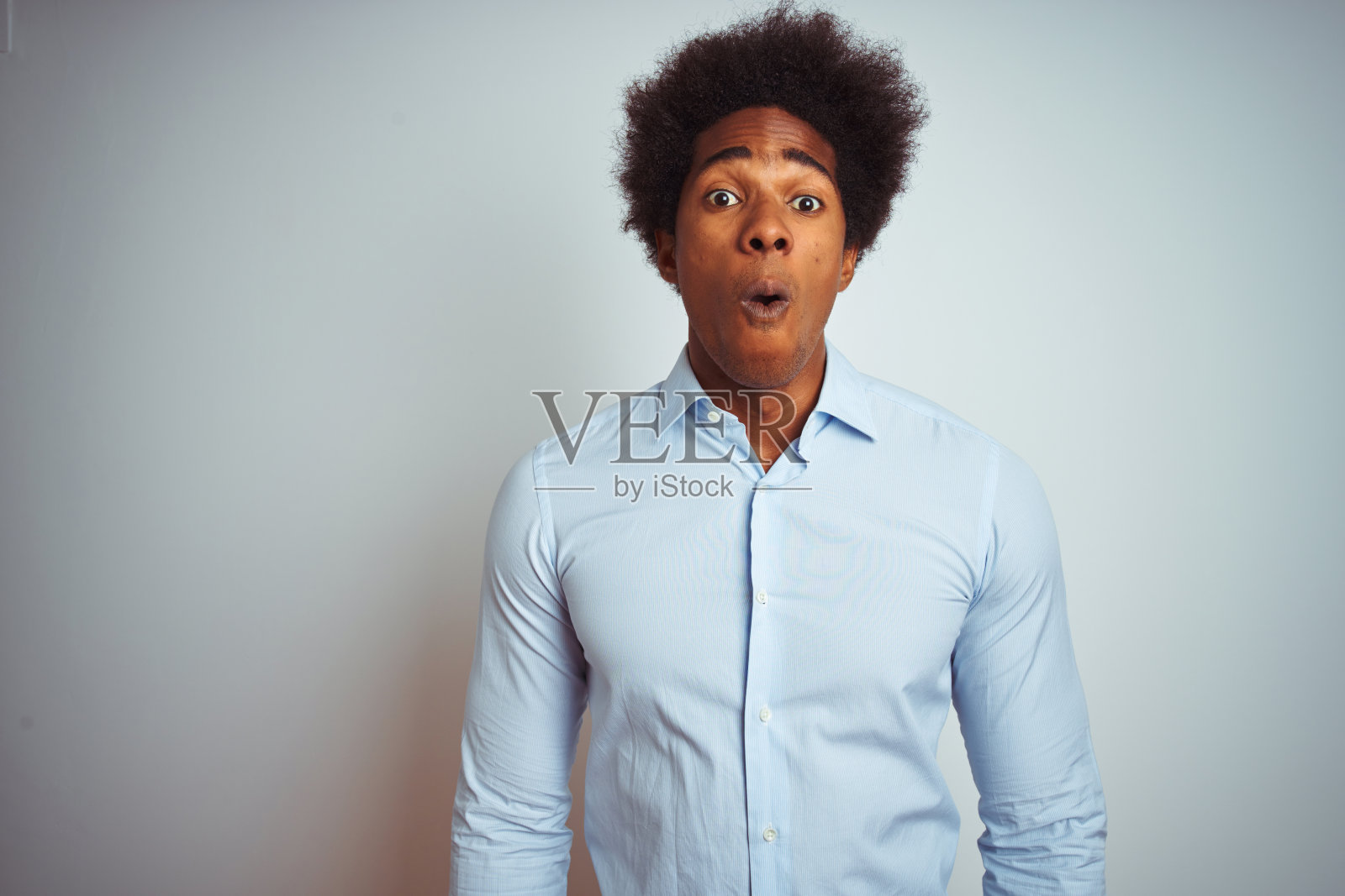 年轻的非洲裔美国人与非洲式的头发穿优雅的衬衫在孤立的白色背景害怕和震惊与惊讶的表情，恐惧和兴奋的脸。照片摄影图片