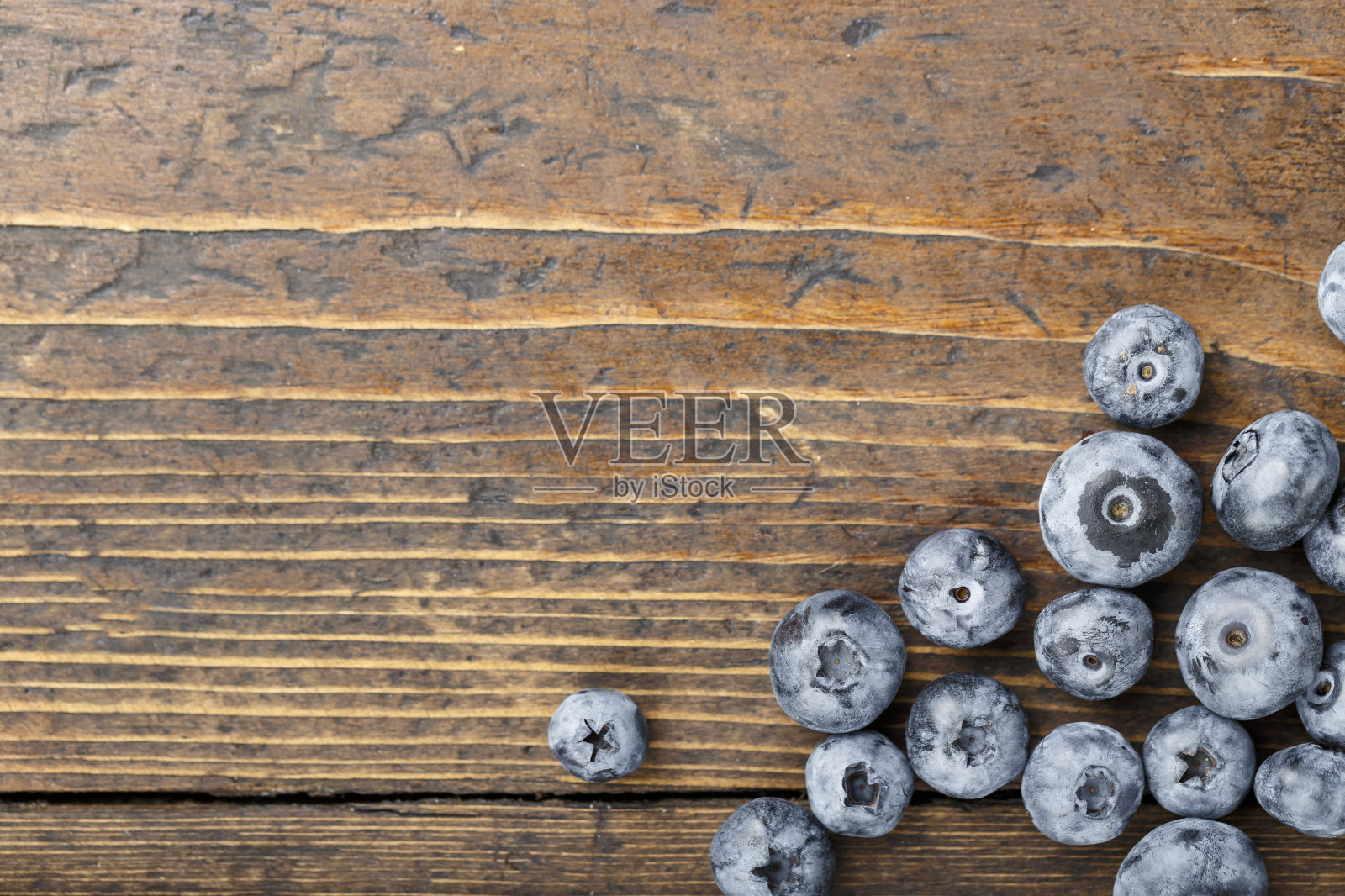成熟的蓝莓散落在棕色的木质背景上。照片摄影图片