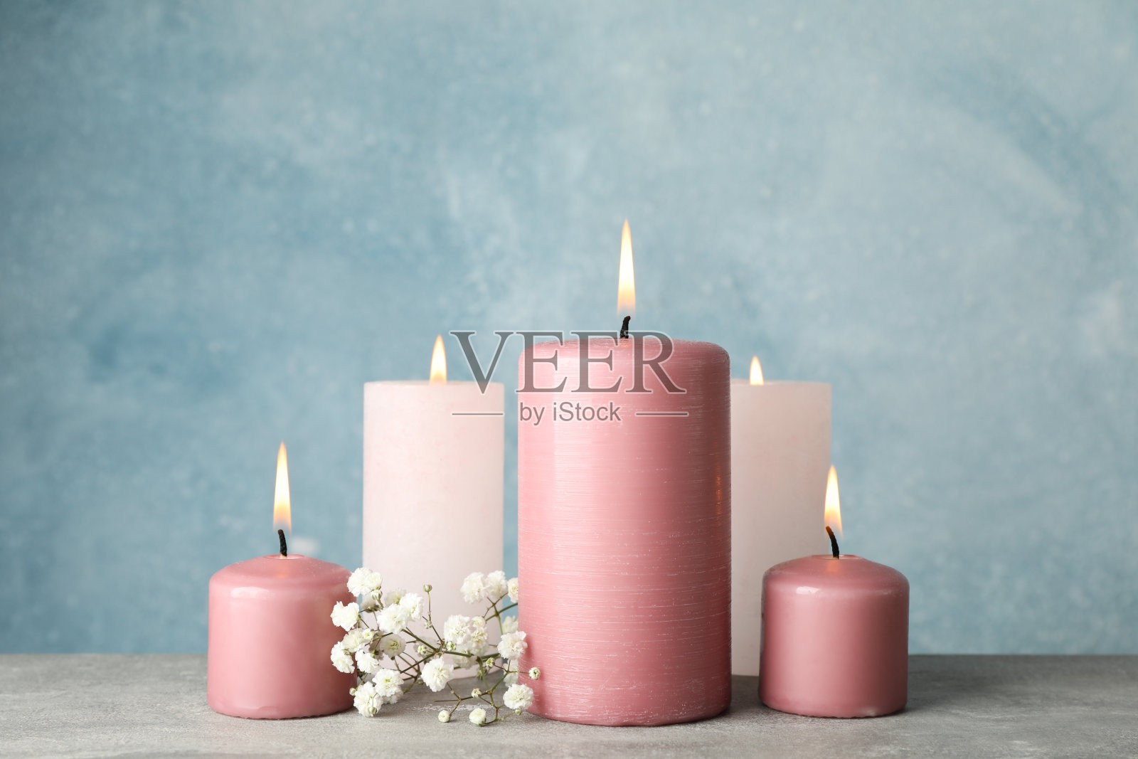 蓝色背景下燃烧的蜡烛和花朵，特写照片摄影图片