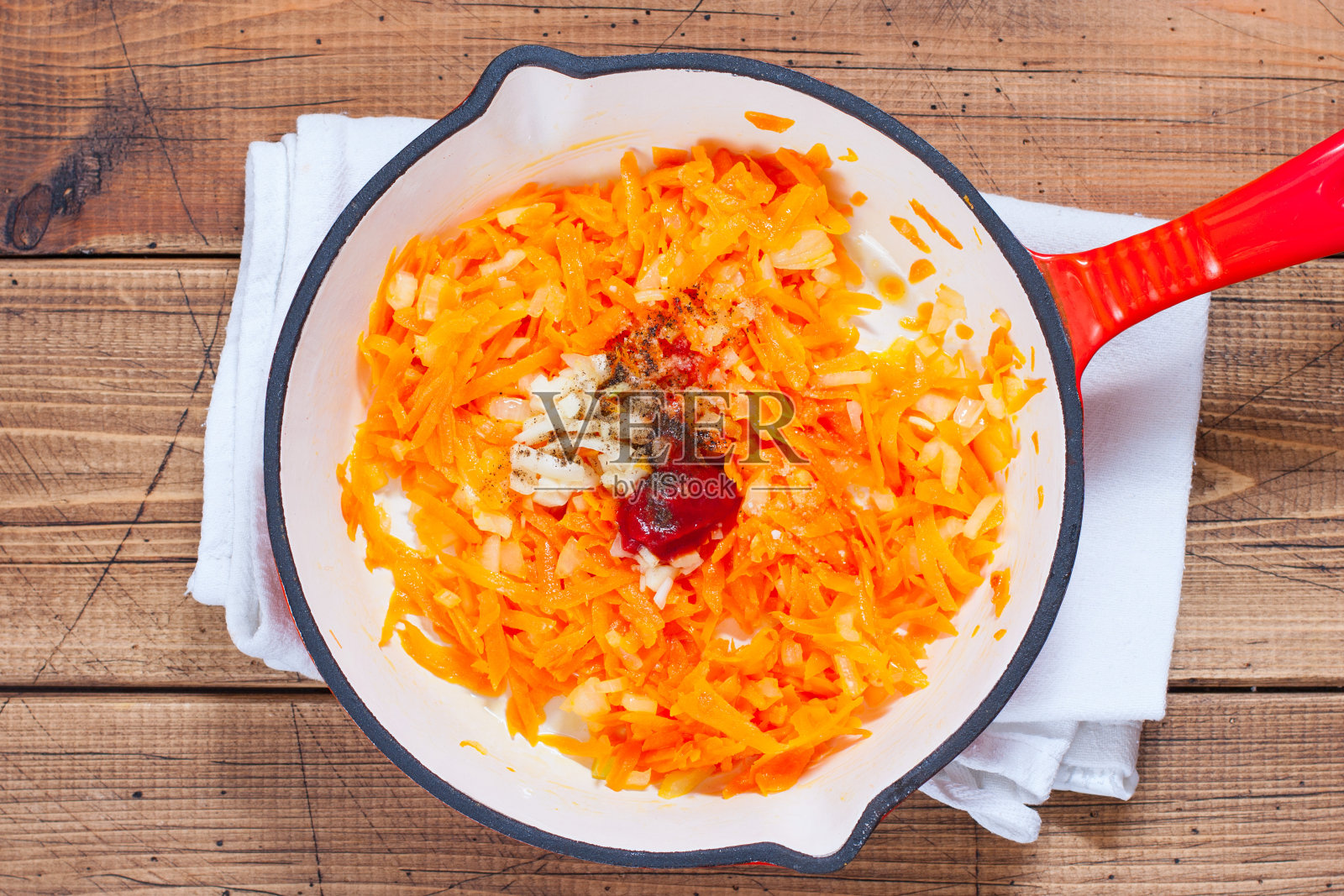 用平底锅一步一步地煎胡萝卜和洋葱，第4步——加入香料和番茄酱，俯视图，选择性聚焦照片摄影图片