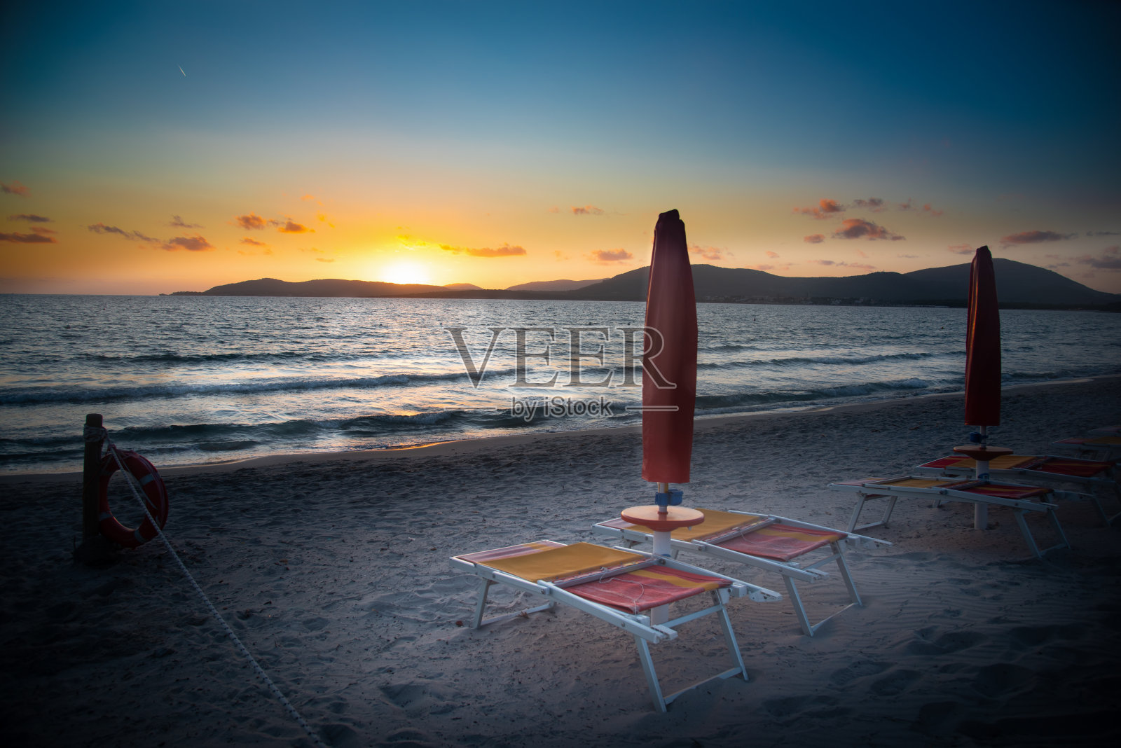 日落时海边的沙滩椅和阳伞照片摄影图片