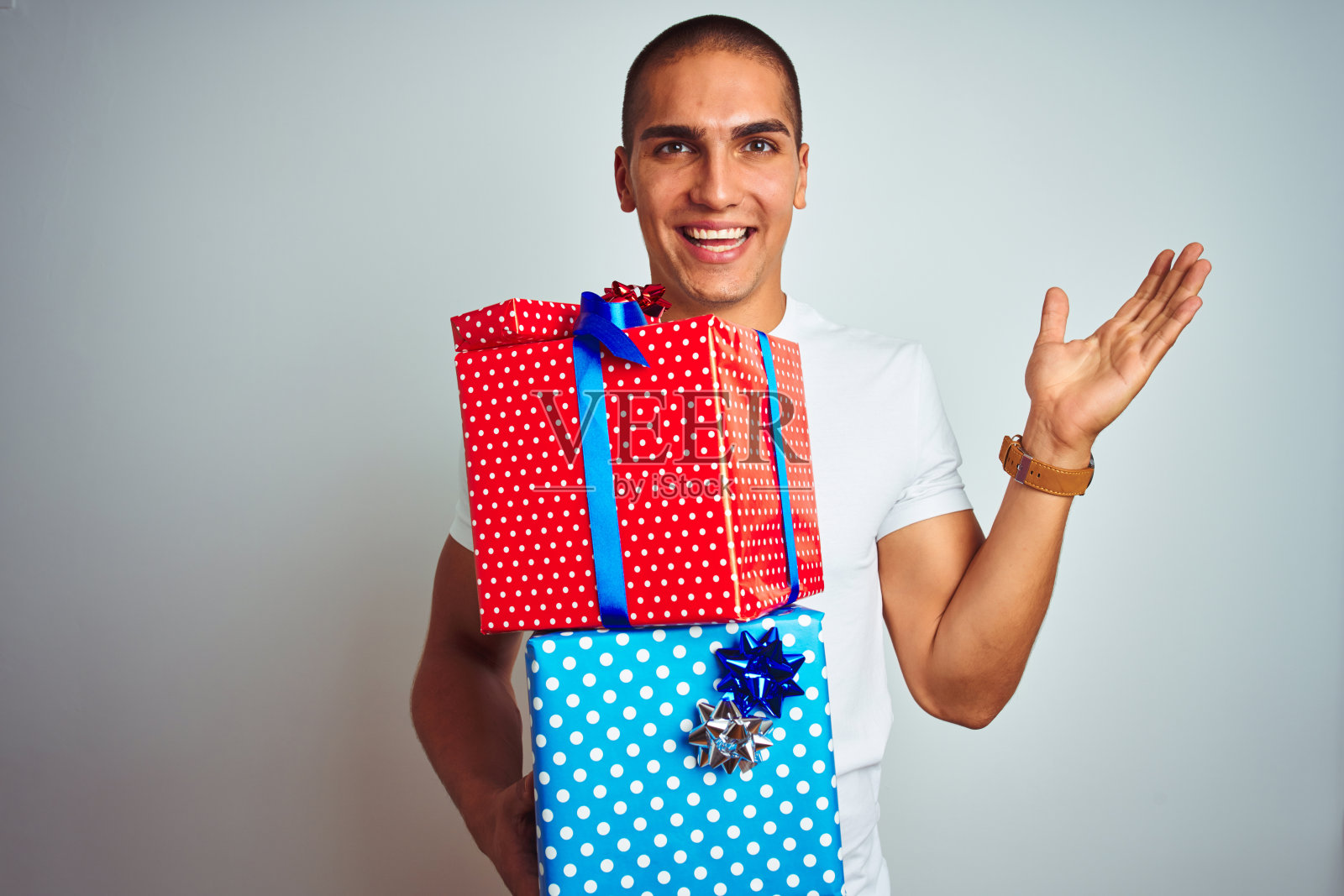 年轻英俊的男人拿着生日礼物越过白色孤立的背景非常高兴和兴奋，胜利者的表情庆祝胜利尖叫着大大的微笑和举起手照片摄影图片