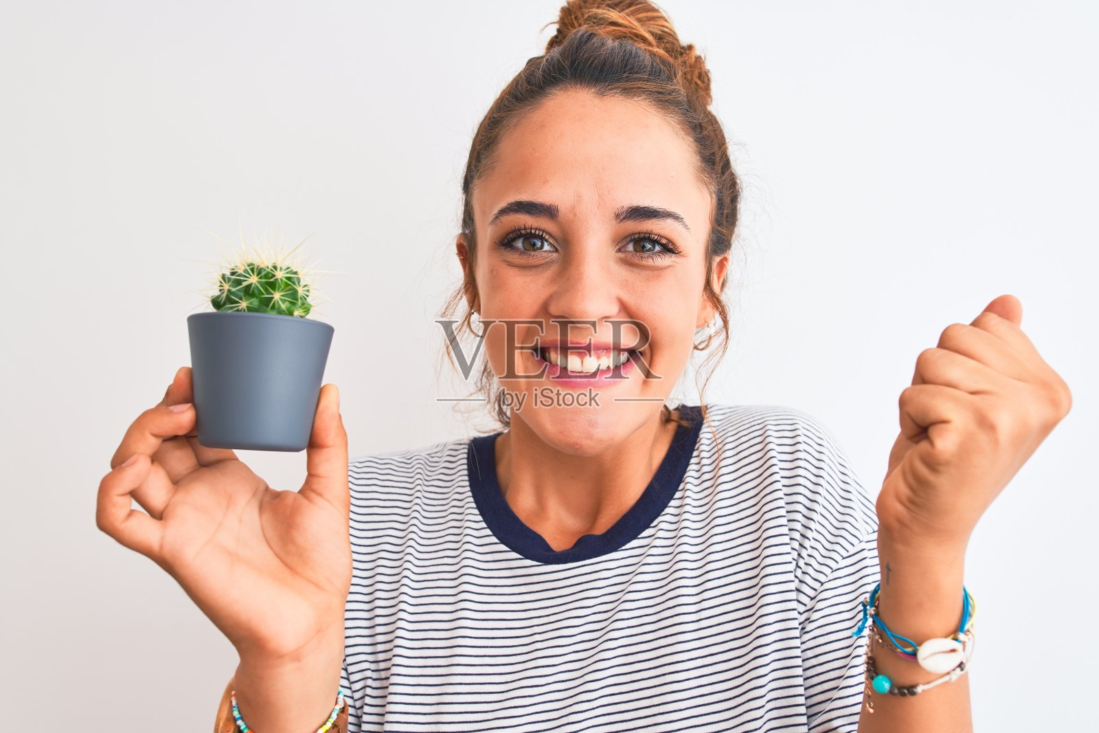 一个年轻的红发女人拿着仙人掌花盆在孤立的背景上尖叫自豪，庆祝胜利和成功非常兴奋，欢呼的情绪照片摄影图片