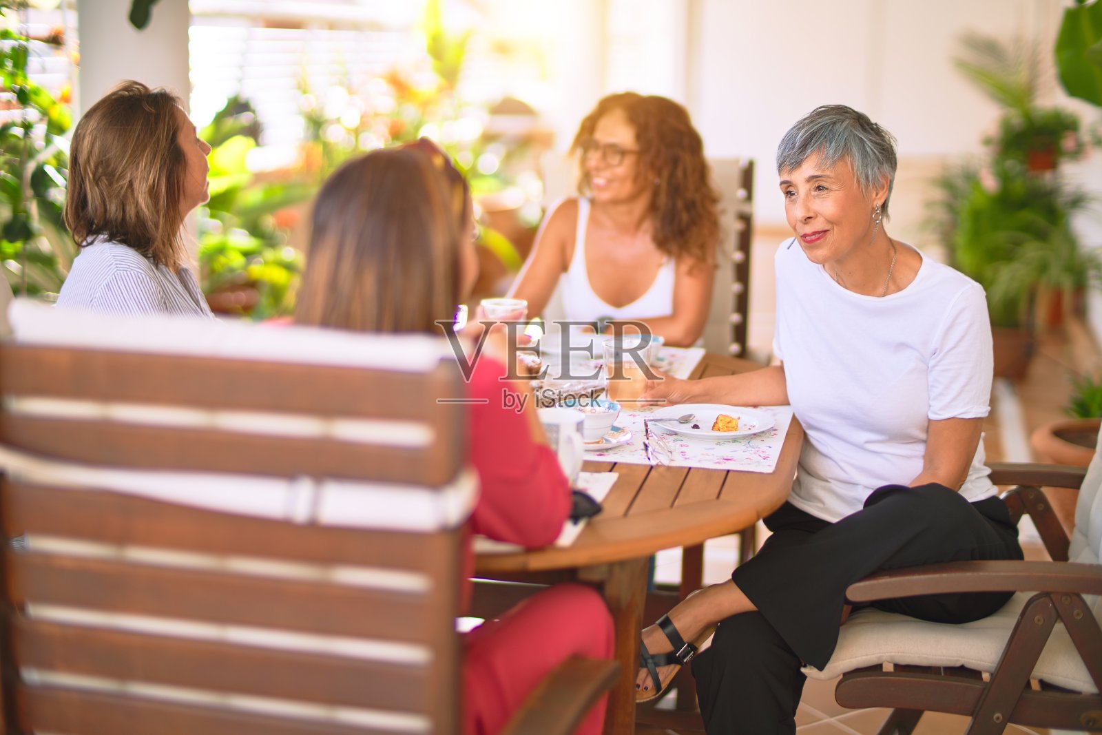 遇见中年妇女吃午饭喝咖啡。阳光灿烂的日子，成熟的朋友在家里开心的微笑照片摄影图片