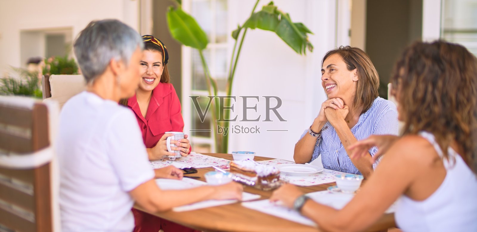 遇见中年妇女吃午饭喝咖啡。阳光灿烂的日子，成熟的朋友在家里开心的微笑照片摄影图片