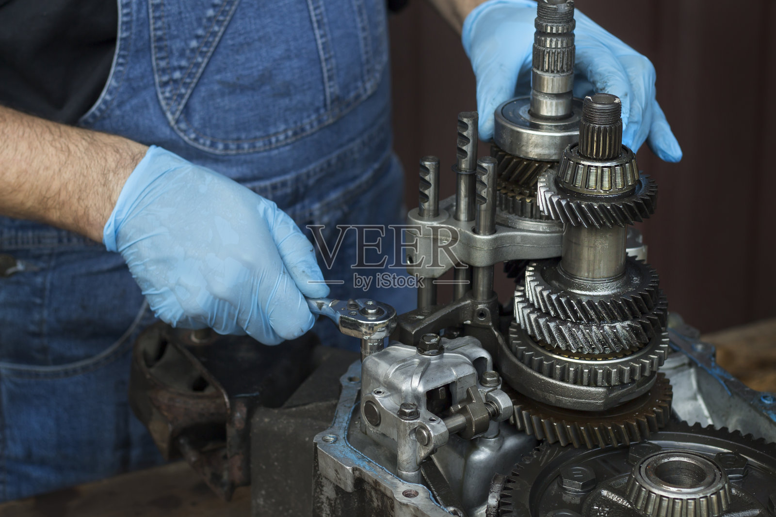 机修工正在修理汽车的变速箱。拧下带损坏变速箱的插座。照片摄影图片