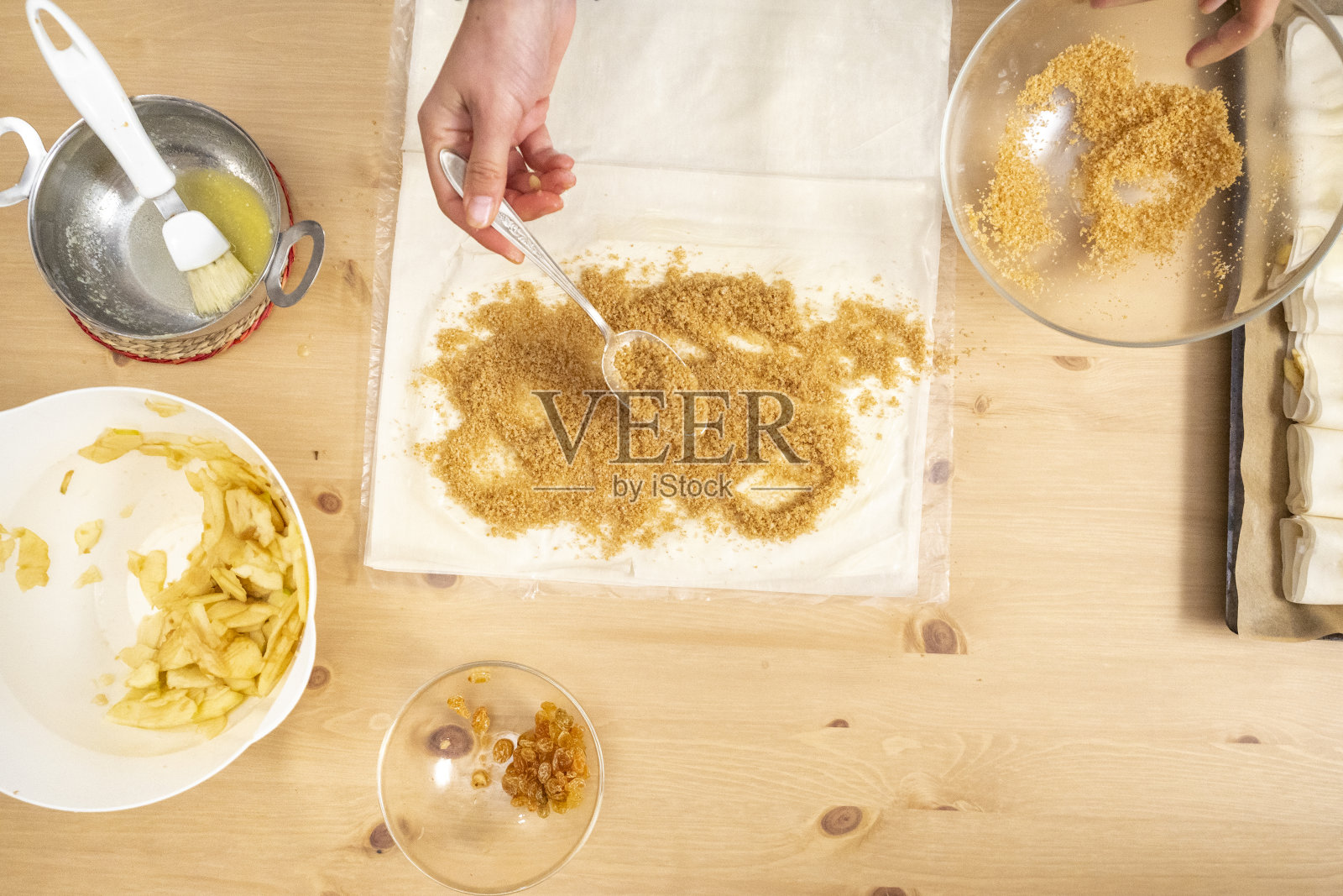 女人的手从上面向菲罗撒面包屑和糖照片摄影图片