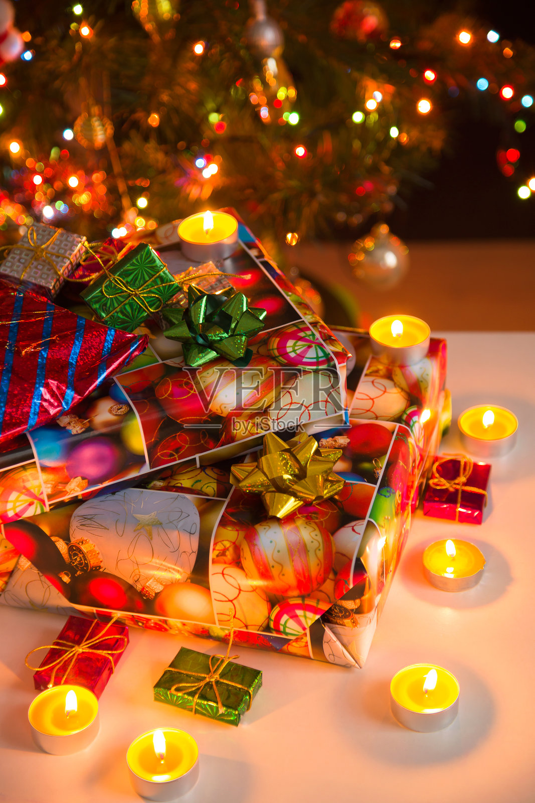 礼物盒和燃烧的蜡烛，在圣诞树下，垂直照片摄影图片