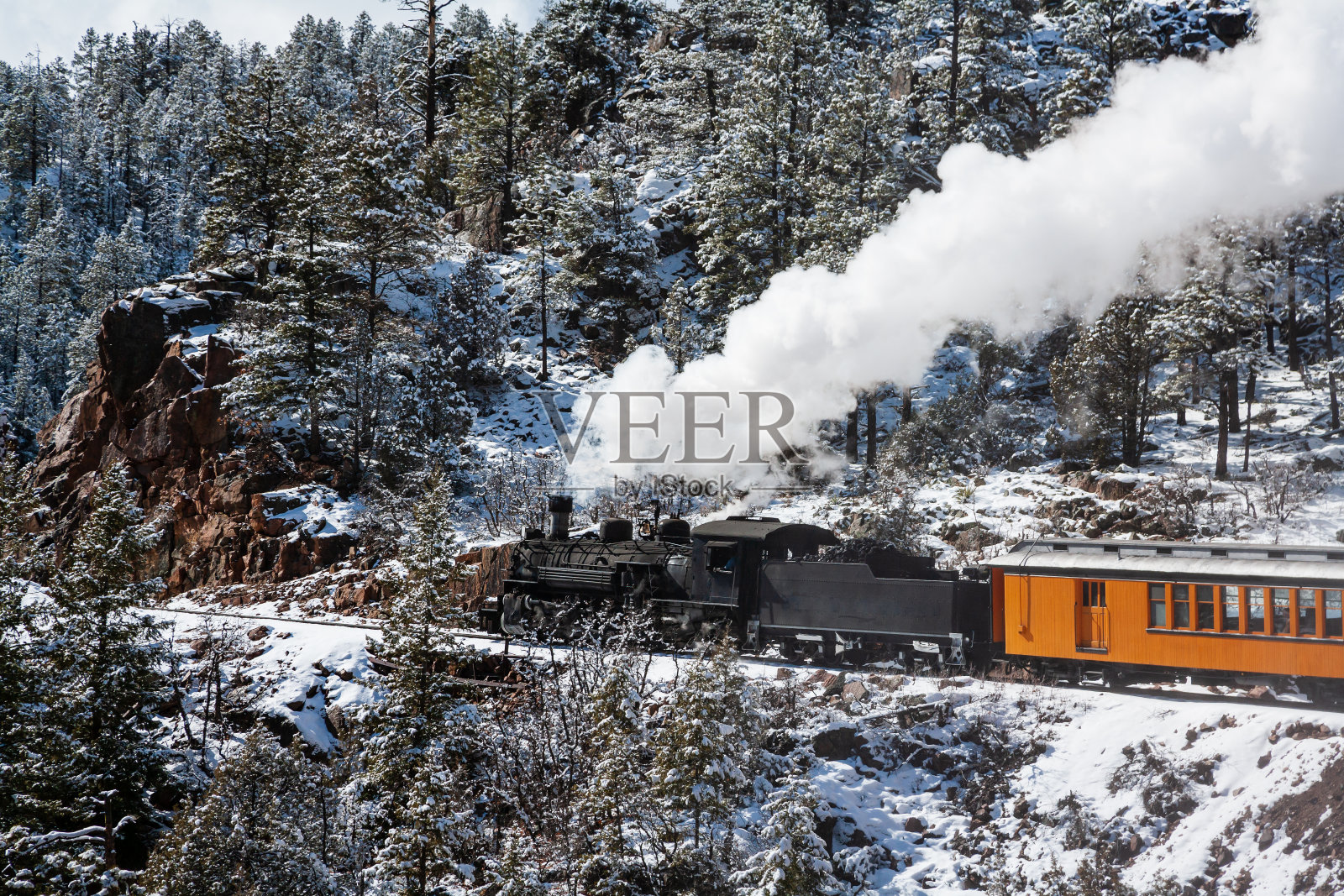 老式蒸汽火车滚滚浓烟通过山脉。照片摄影图片
