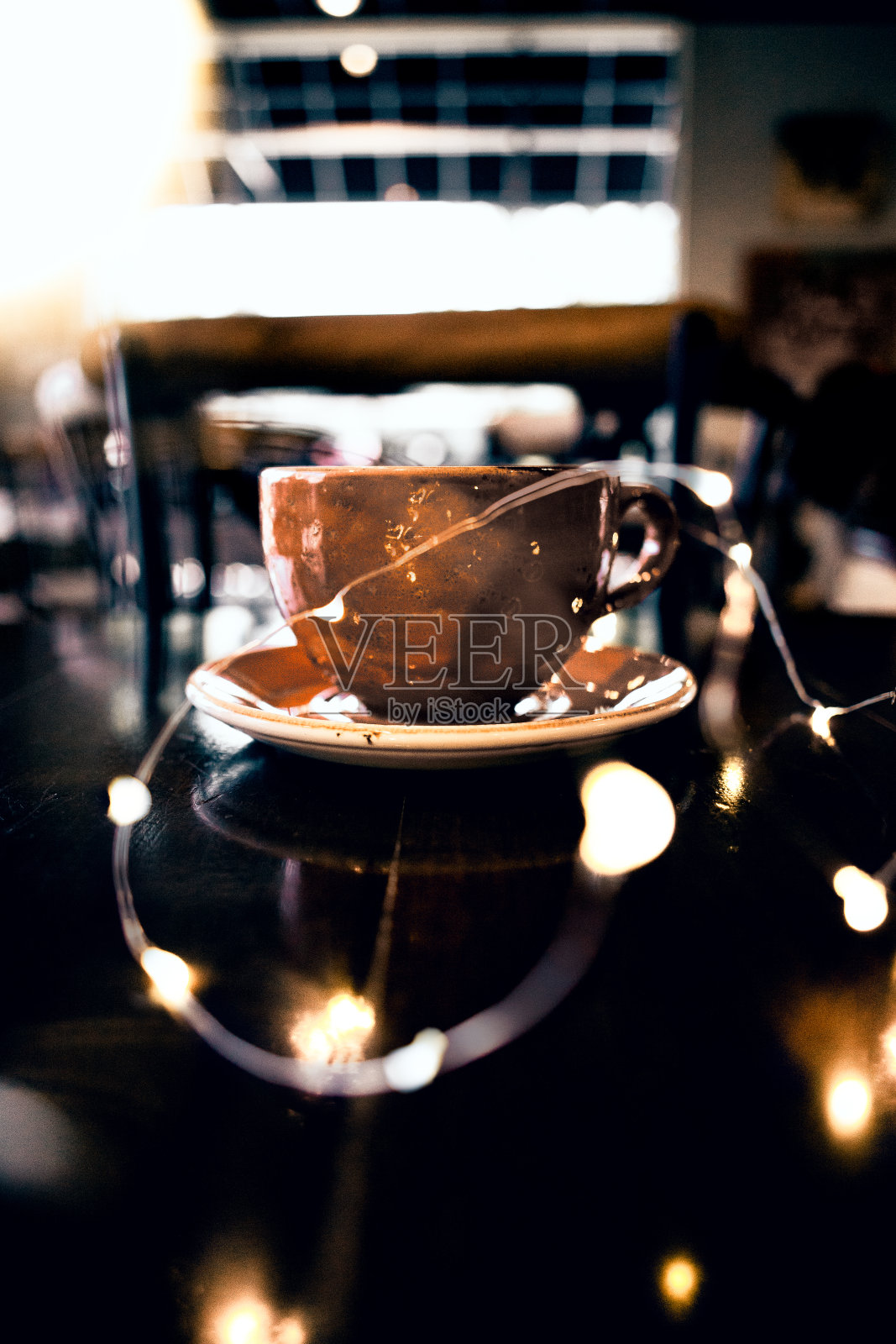 桌上放着一杯咖啡，周围是灯照片摄影图片
