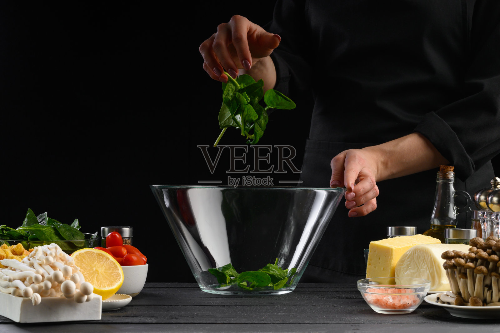 一位专业的厨师正在准备一份新鲜的菠菜叶沙拉，新鲜的原料，素食者和健康的营养。有机食品，黑色背景，水平照片与设计空间照片摄影图片
