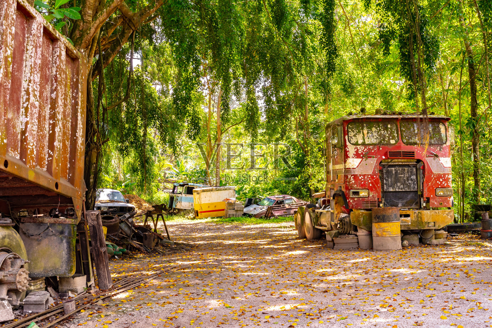 生锈的旧废弃的红色卡车/拖车头在废品场/废品场/废品场和其他废弃的打捞车/车辆周围。照片摄影图片