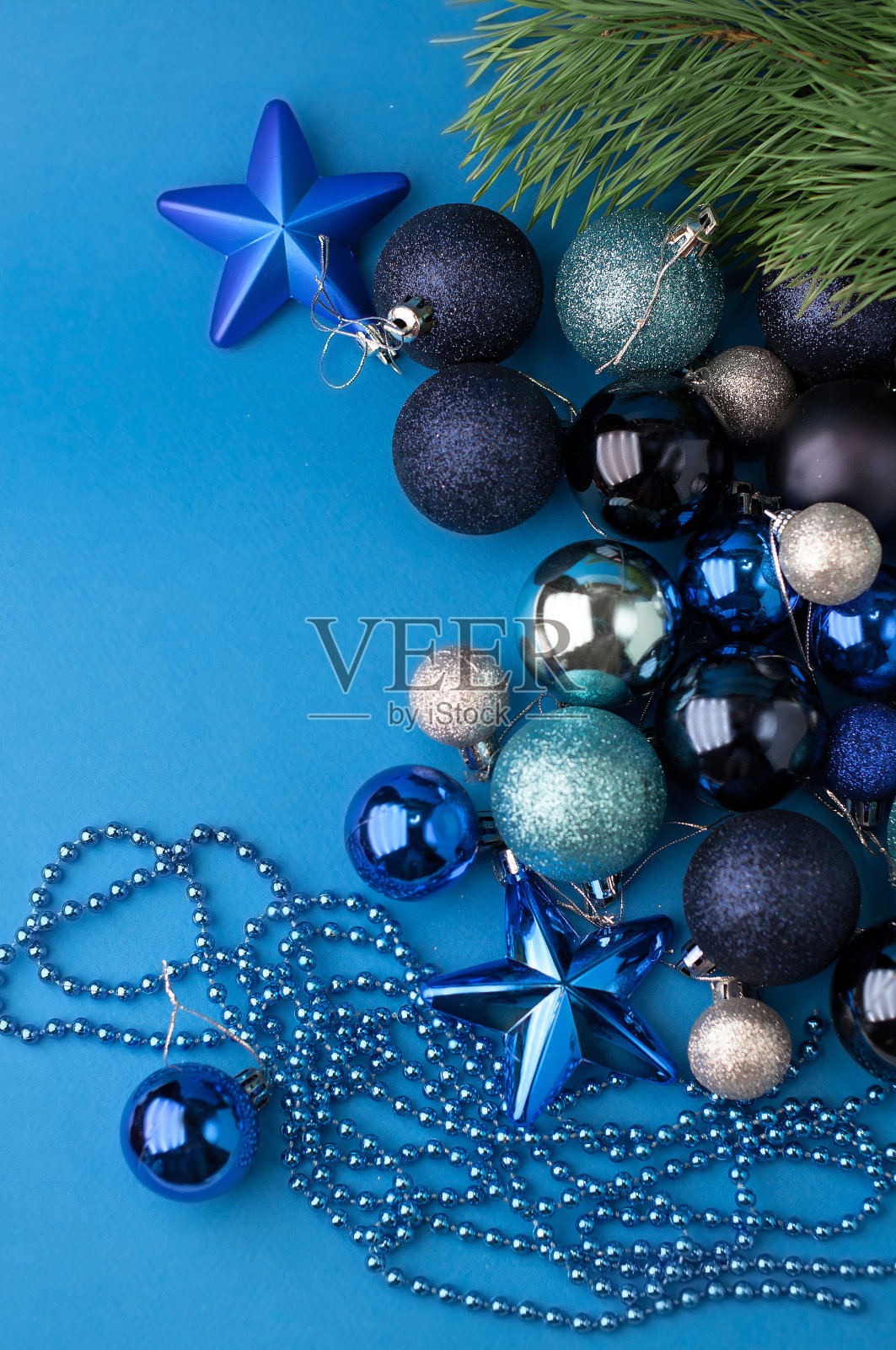 圣诞节喜庆的蓝色背景，上面放着许多不同的蓝色圣诞树玩具，带着礼物和彩珠照片摄影图片