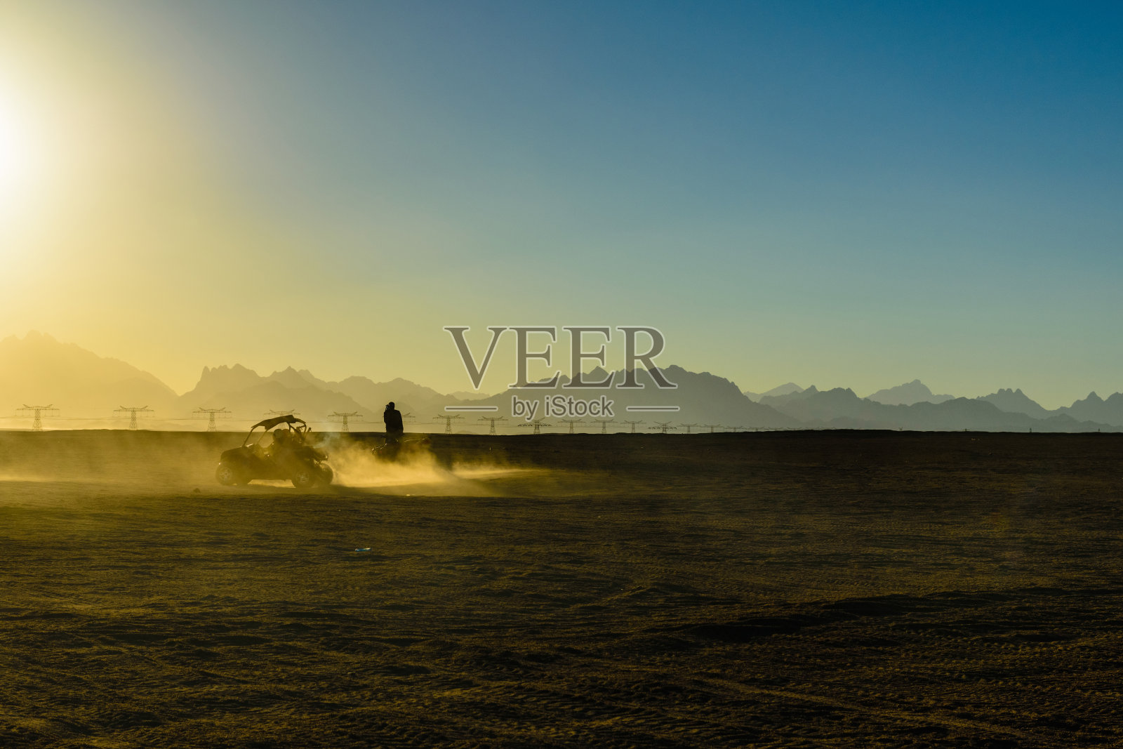 在日落时分，于埃及洪加达市附近的阿拉伯沙漠中，难以辨认的人们在参加越野旅行时驾驶着越野车照片摄影图片