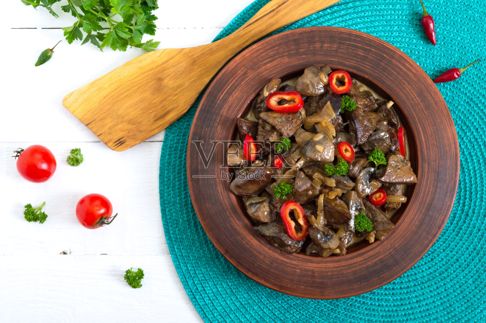 白木头背景上的泥碗里放着几片洋葱炒火鸡肝。饮食菜单。前视图。照片摄影图片