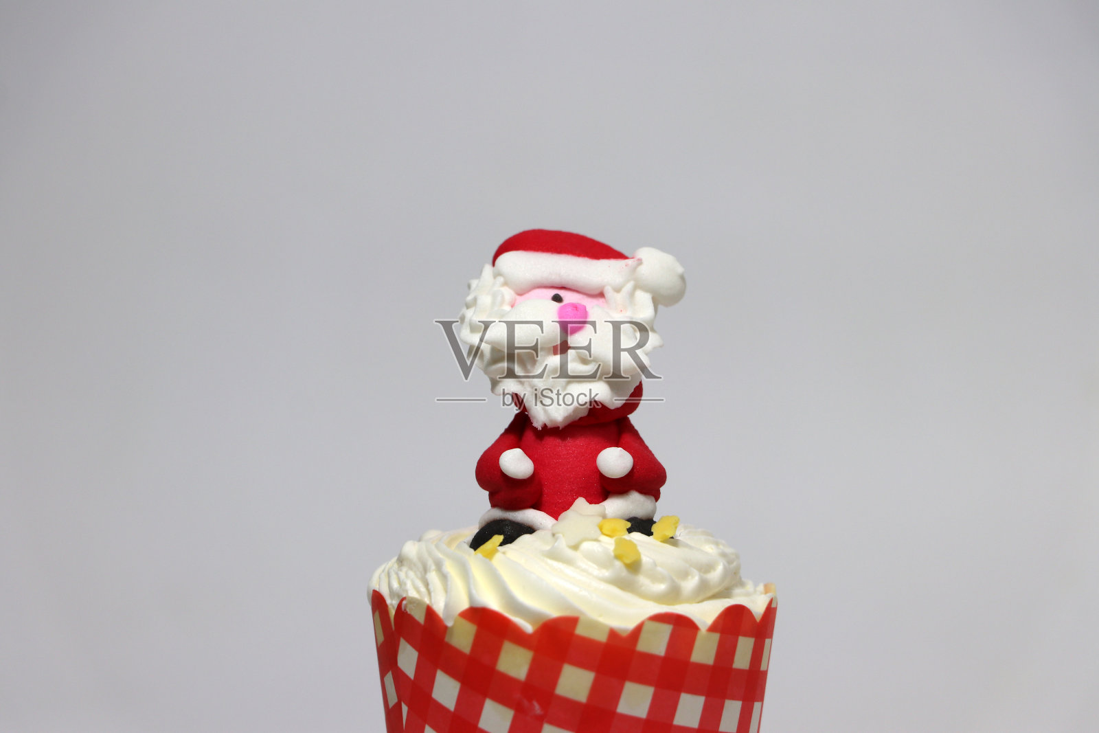 以圣诞老人为背景的圣诞纸杯蛋糕。照片摄影图片