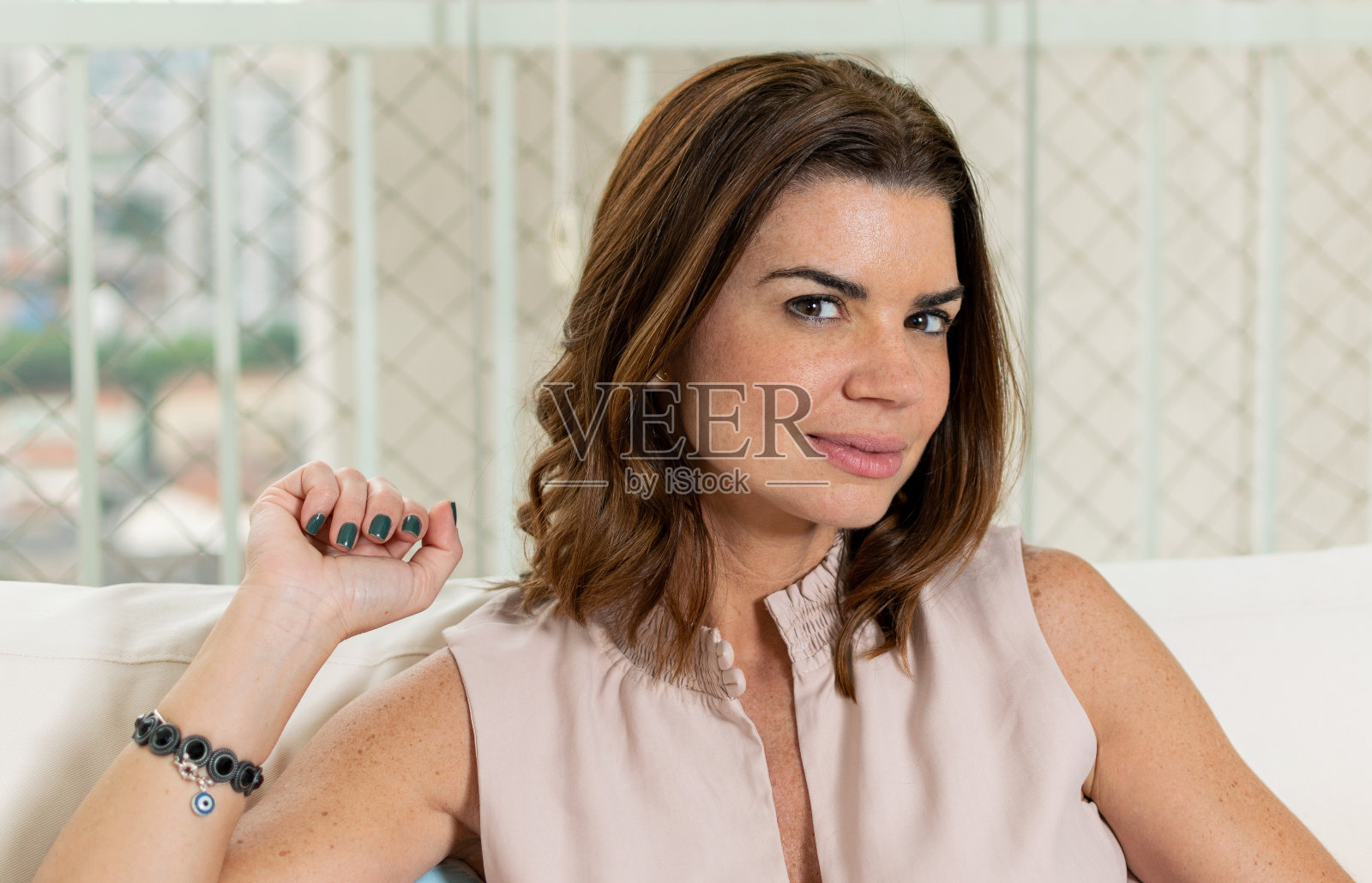 一个38岁的女人坐在她的家庭办公室里，坐在沙发上看着摄像机。照片摄影图片