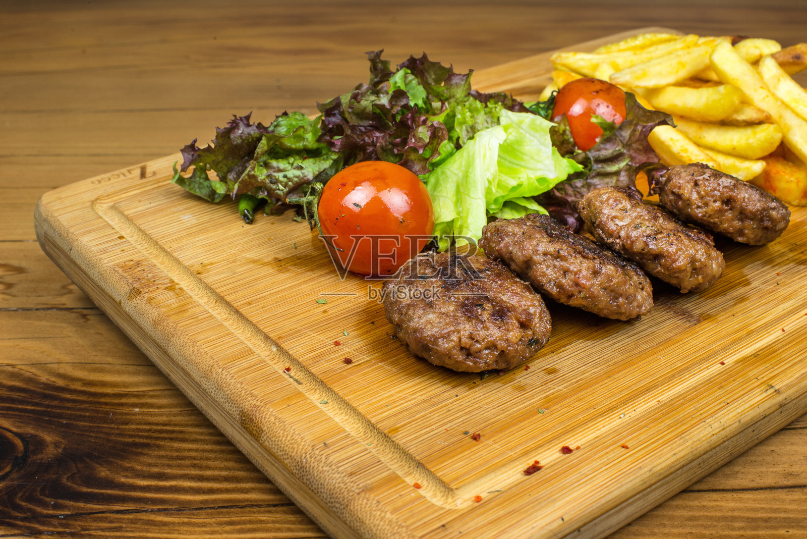 木桌上的木盘里装着美味的自制肉丸、薯条和蔬菜照片摄影图片