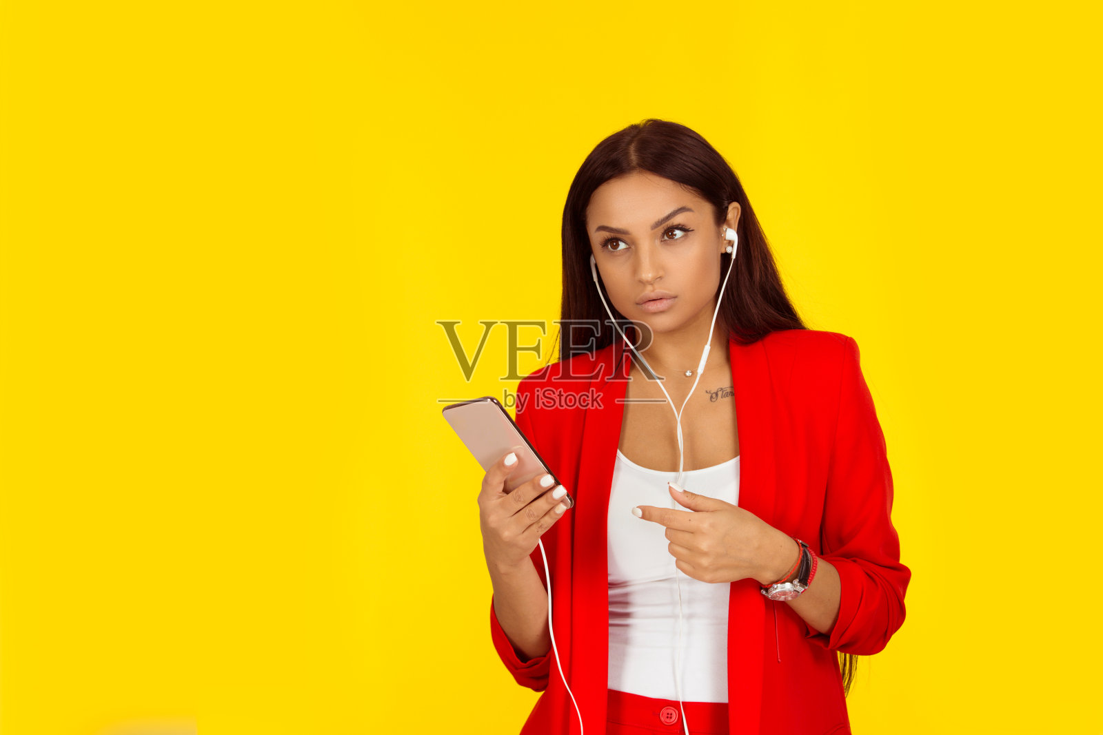 女孩戴着耳机，拿着手机仔细听着。照片摄影图片