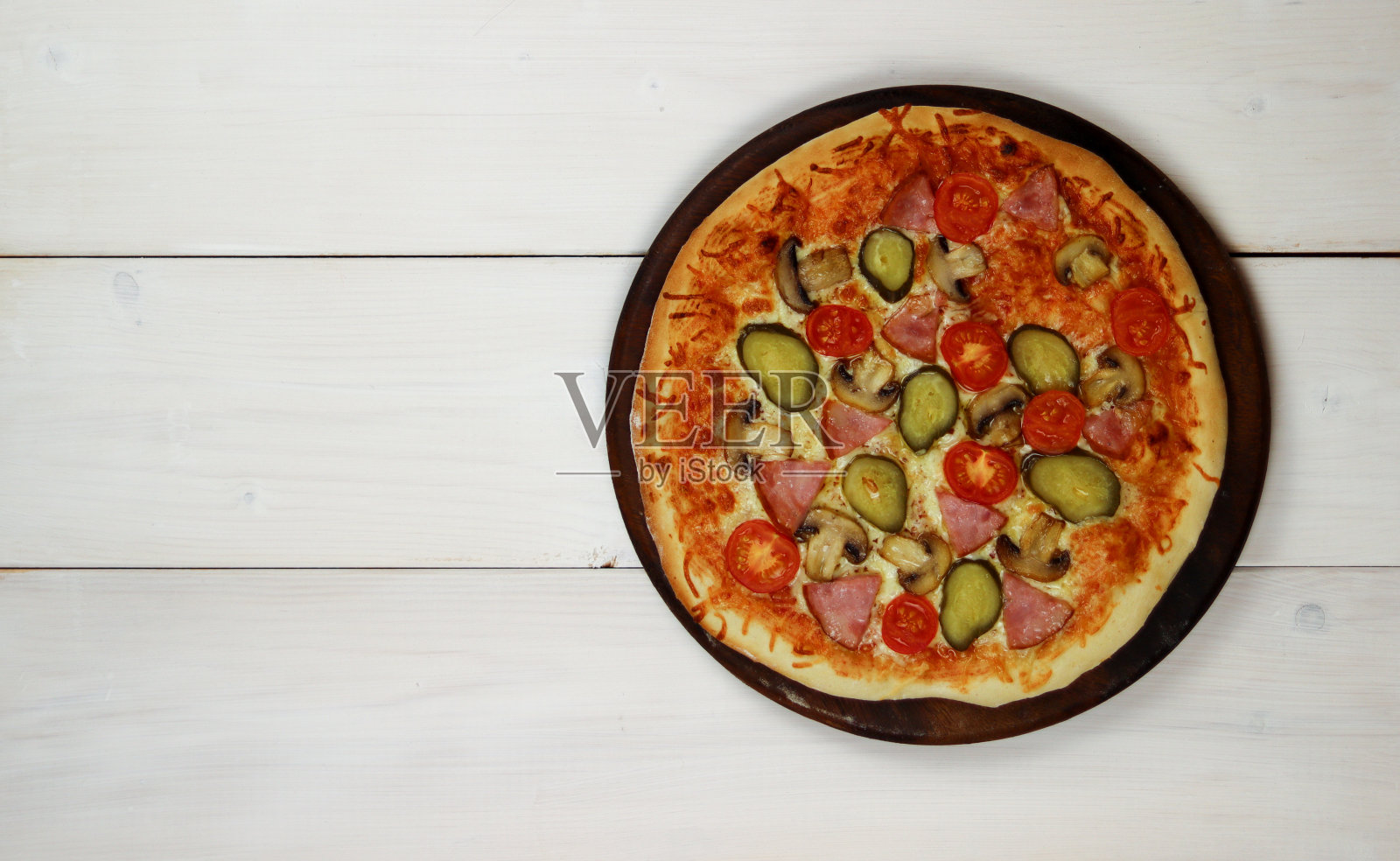 有火腿、蘑菇、圣女果和腌黄瓜的披萨照片摄影图片