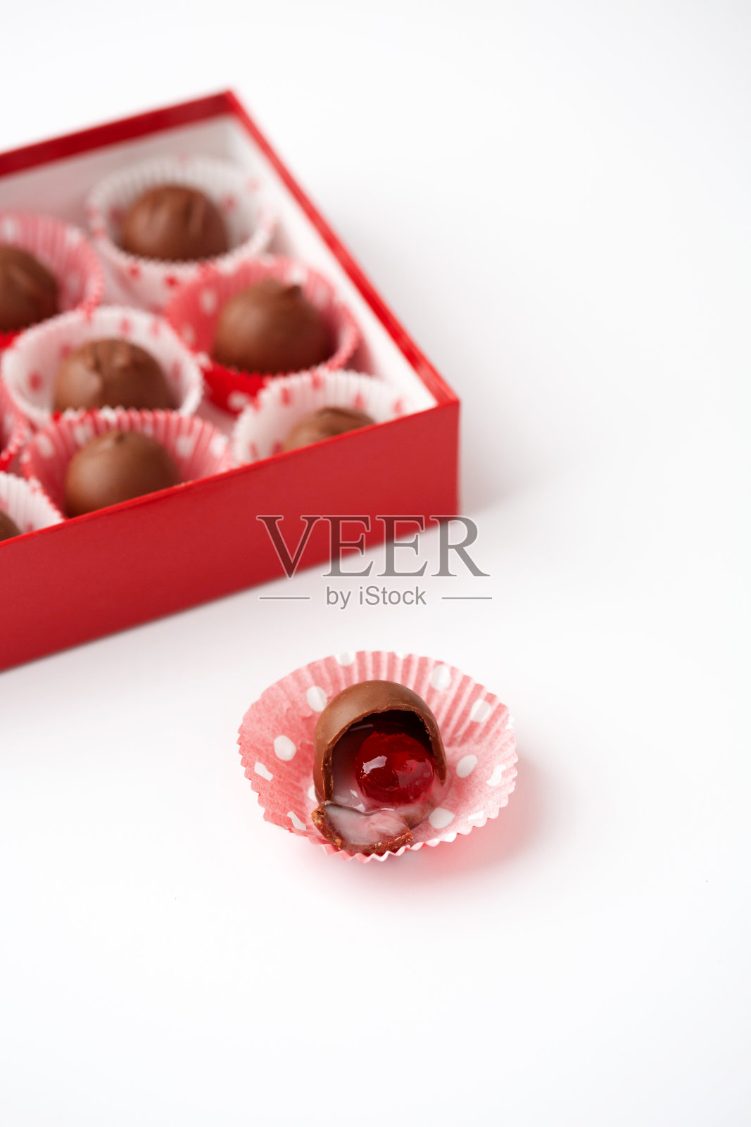 红色盒子的巧克力覆盖樱桃在红白圆点纸;孤立在前方;白色背景照片摄影图片
