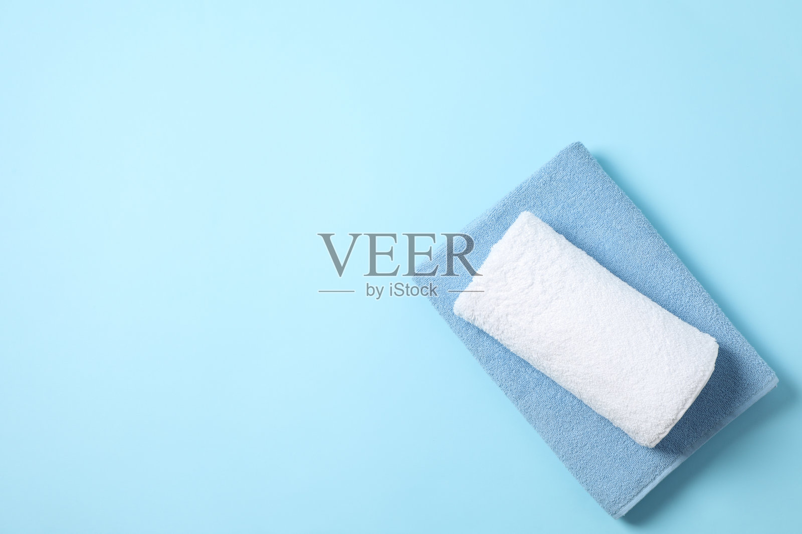 折叠的彩色毛巾在蓝色背景，文字空间照片摄影图片