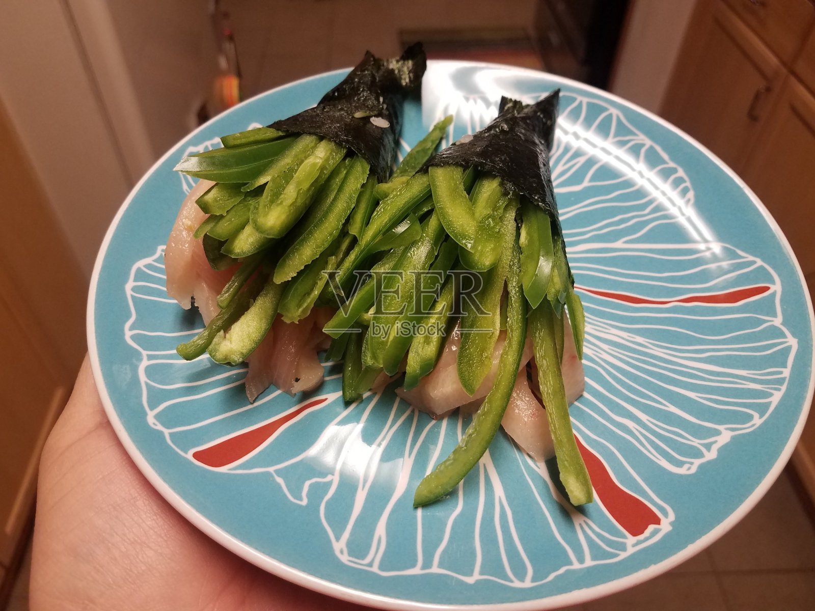 手握寿司卷与辣青椒和鱼照片摄影图片