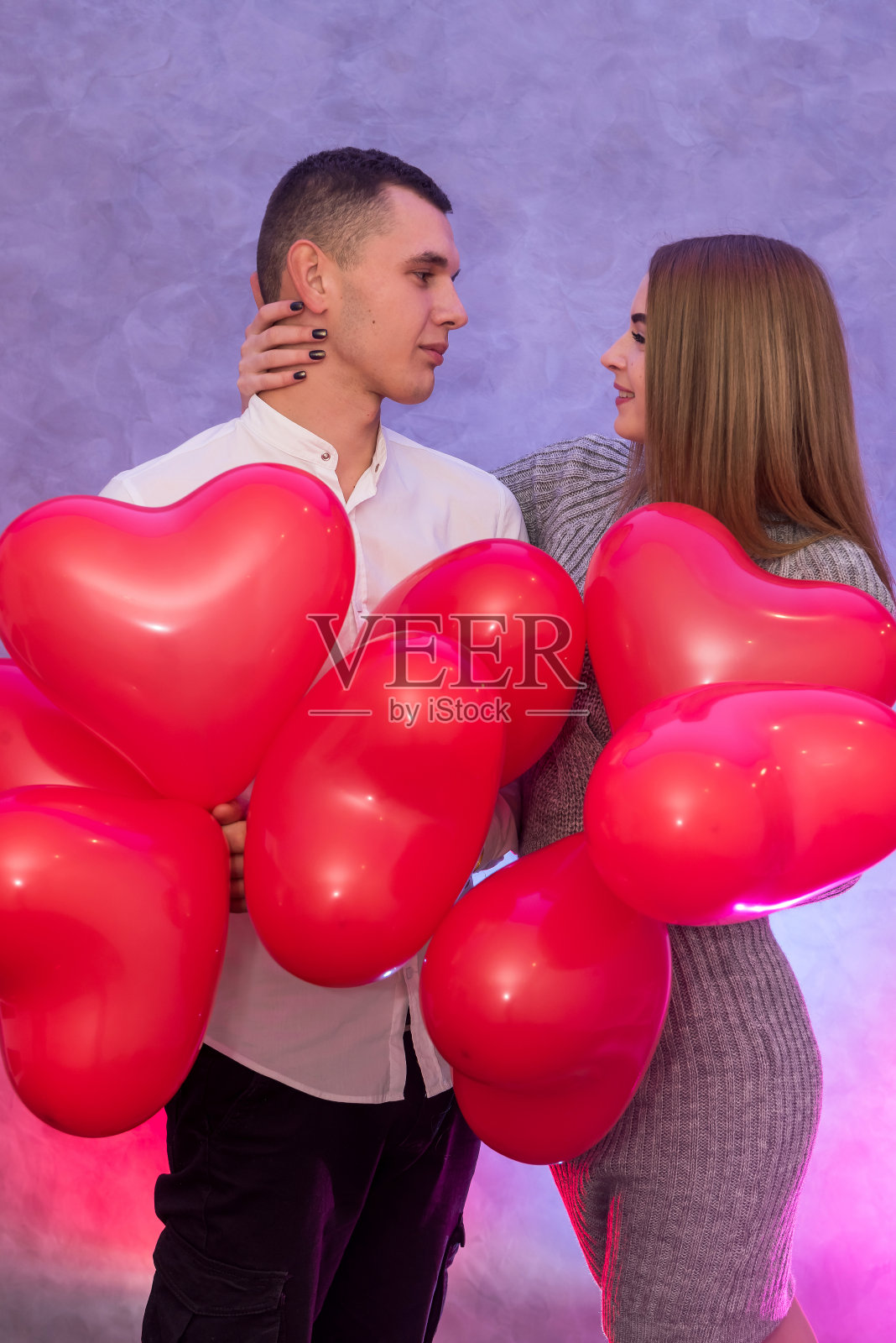 一对美丽的夫妇拿着红色的气球在工作室里摆姿势庆祝情人节照片摄影图片