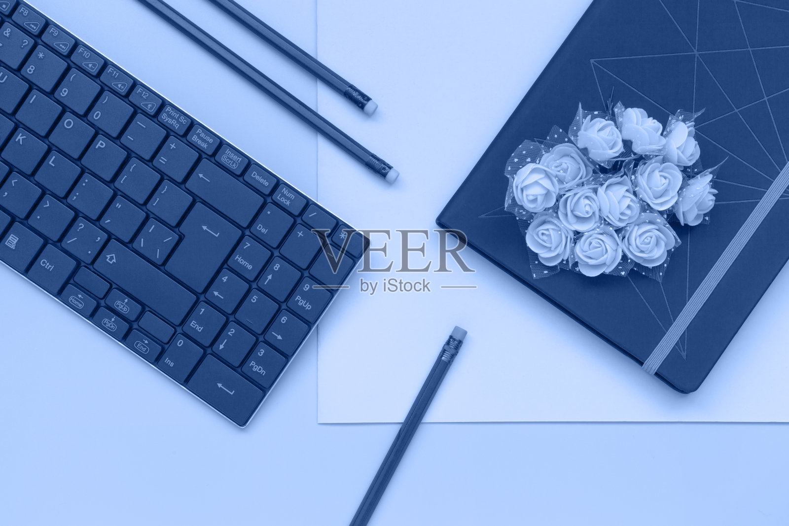 俯视图，笔记本与花和铅笔与键盘在蓝色和粉红色的背景。平铺风格，调和2020年流行经典蓝色照片摄影图片