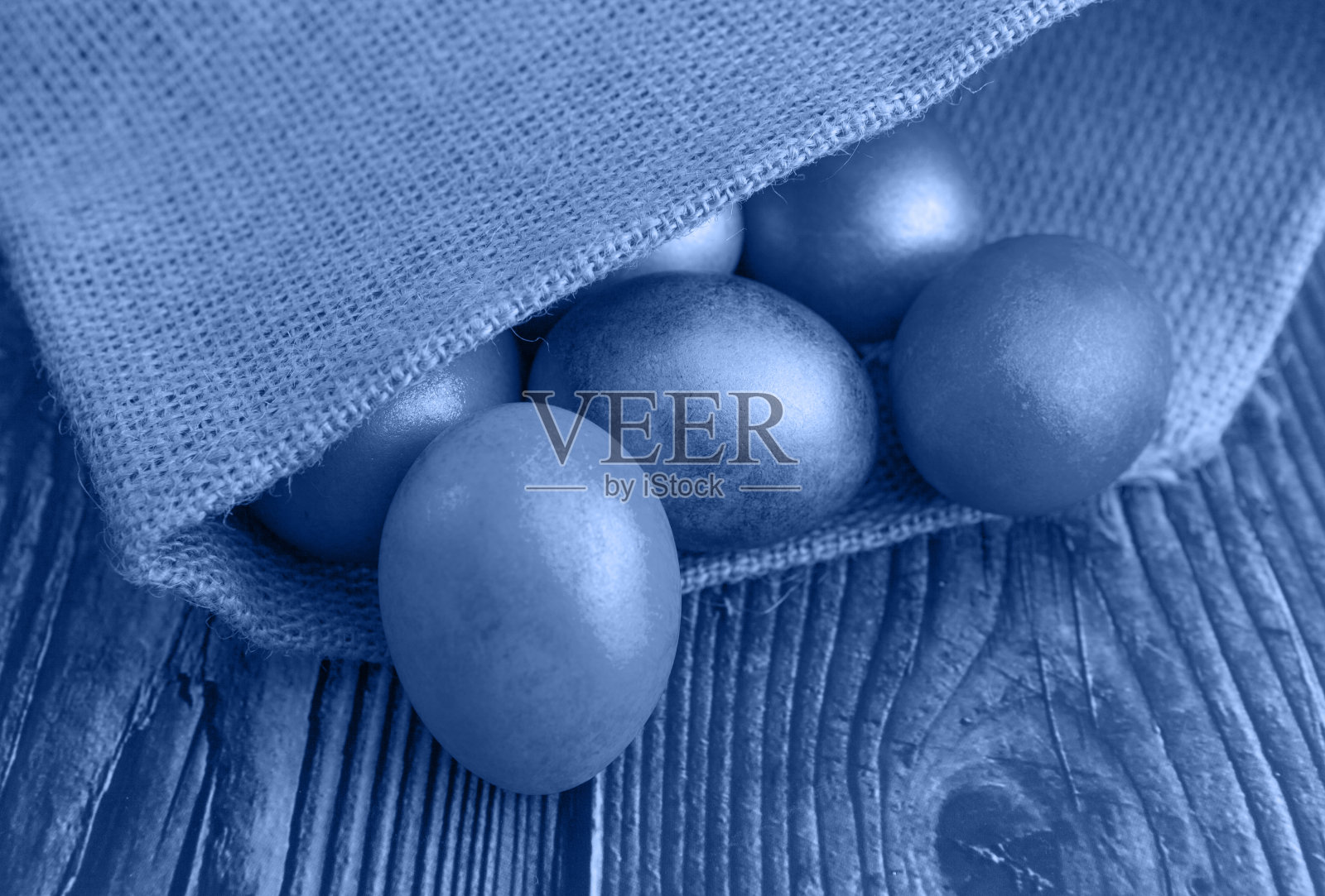 以粗麻布为背景的彩色复活节彩蛋，衬托出2020年流行的经典蓝色照片摄影图片