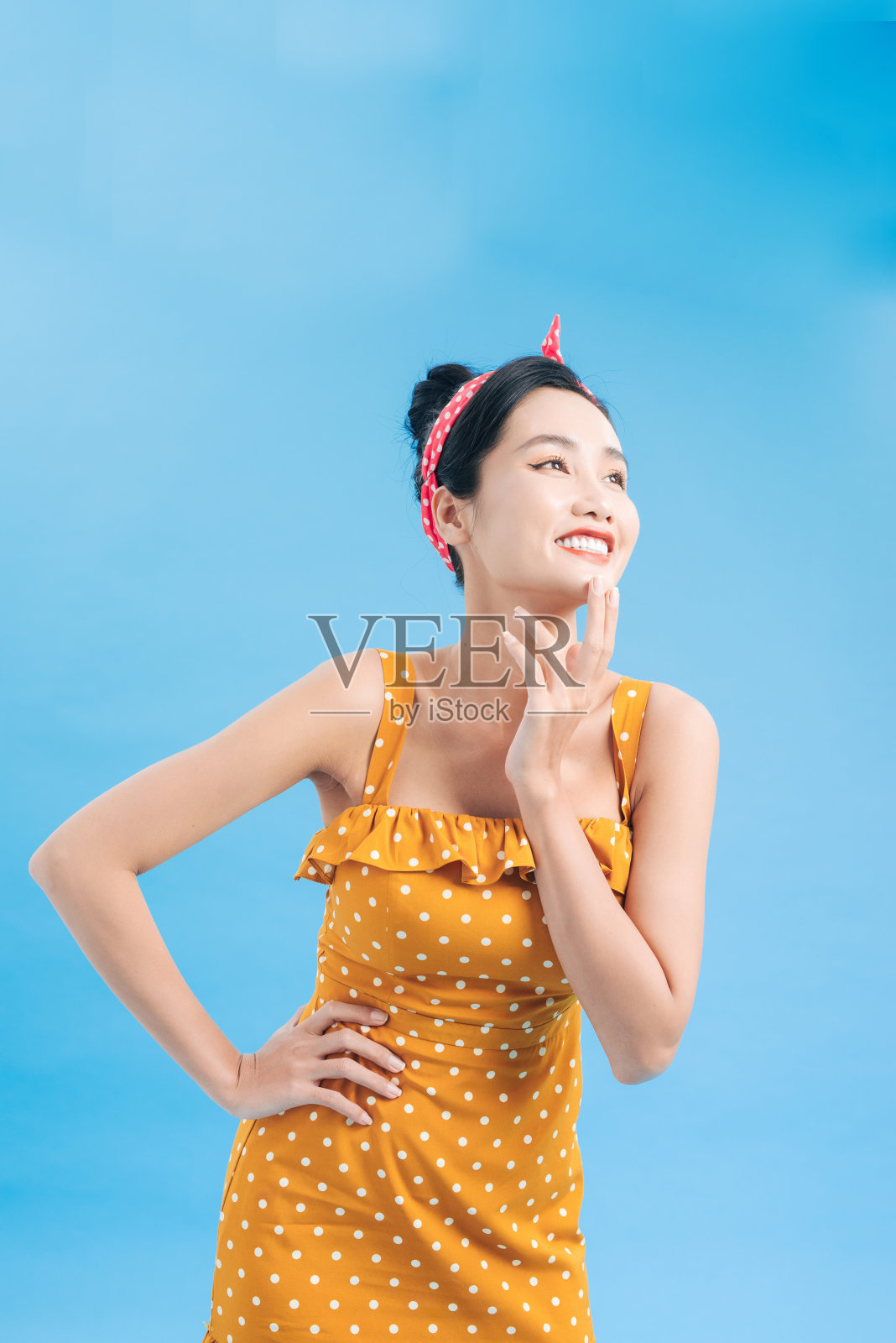 充满灵感的女性在蓝色背景上俏皮地摆姿势：身穿短裙的迷人女郎享受拍摄照片摄影图片