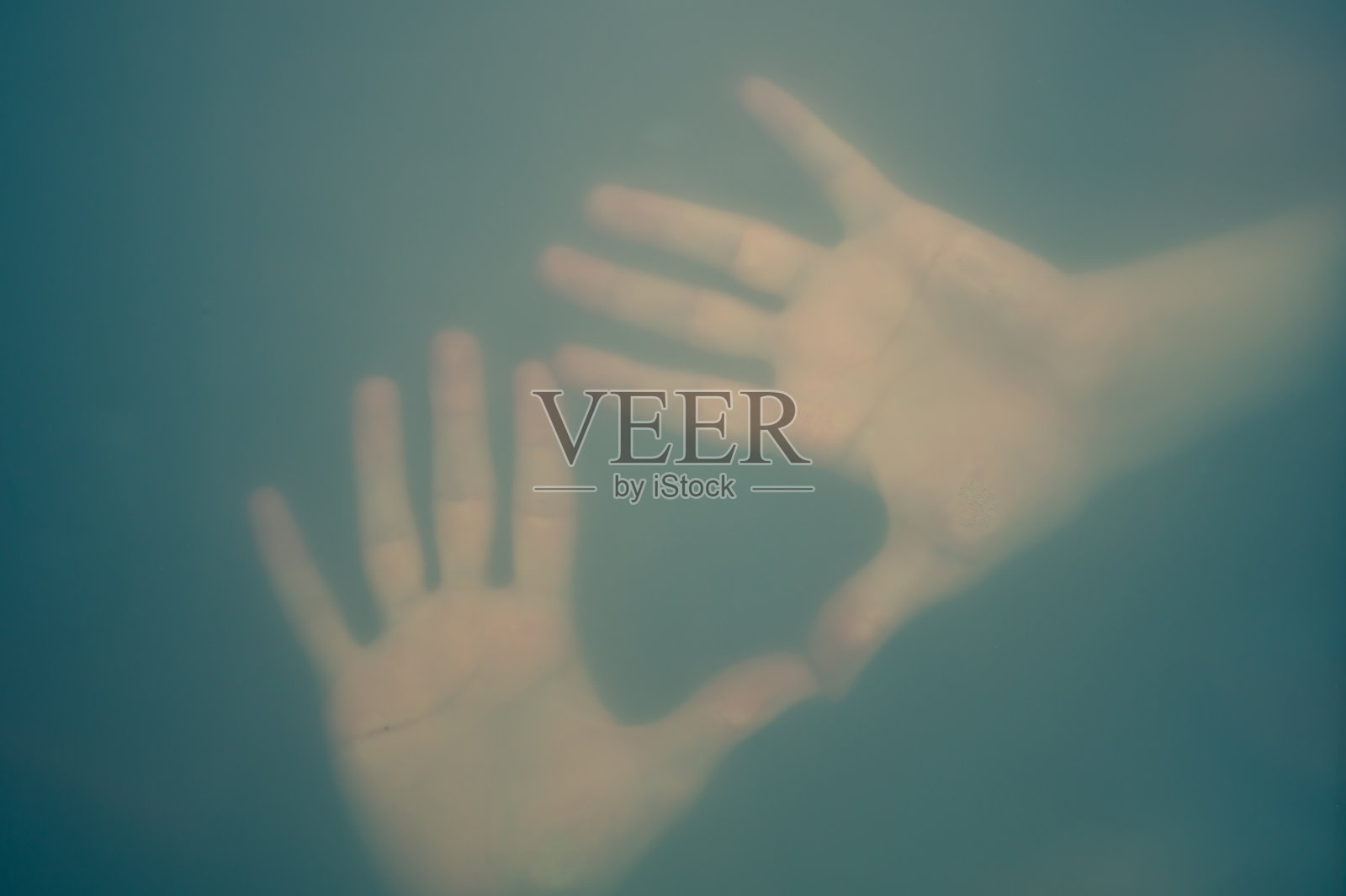 磨砂玻璃后面的手。 雾中的手部轮廓。 孤独的概念。 手掌触摸玻璃窗照片摄影图片