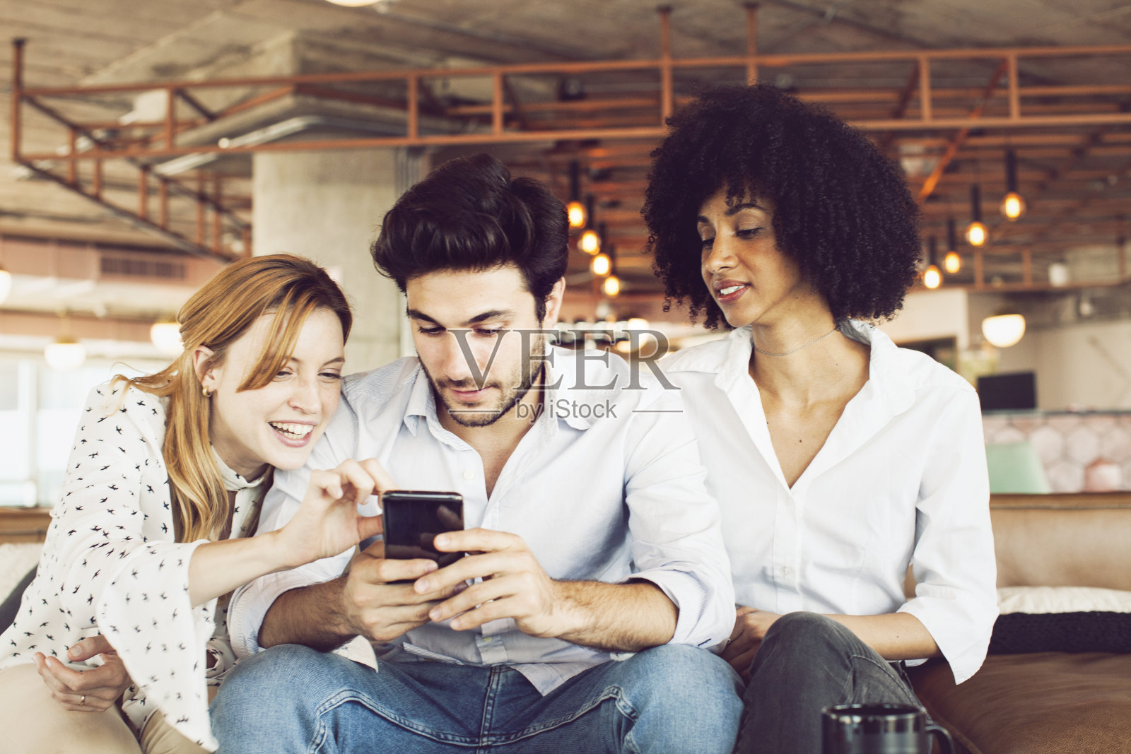 一群朋友坐在沙发上玩手机照片摄影图片