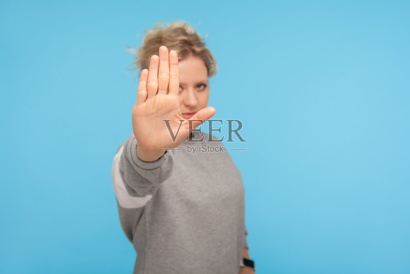 否认,拒绝概念。年轻女子短发在运动衫显示停止手势，没有标志照片摄影图片