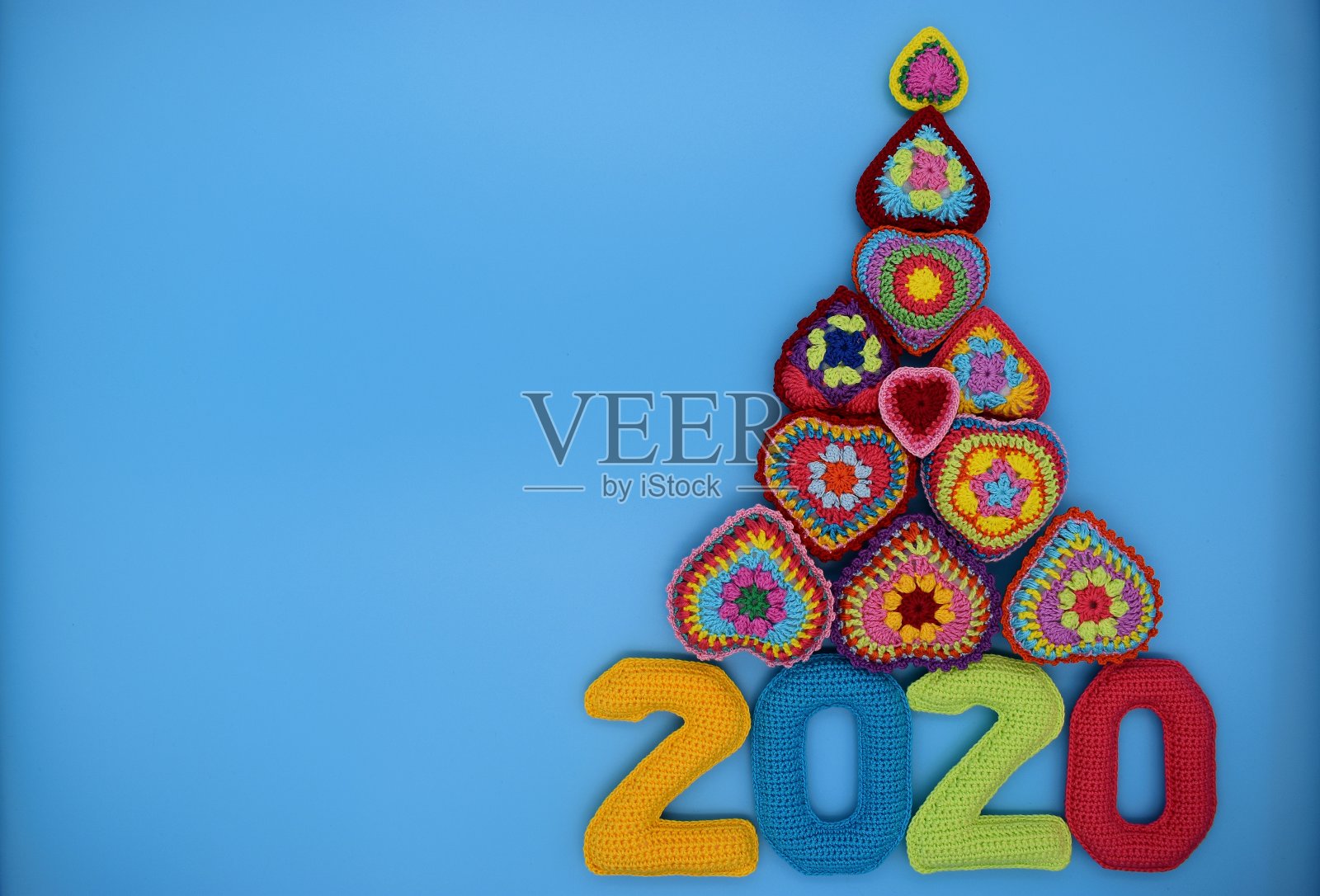 2020年新年。在蓝色背景上编织彩色数字和心形圣诞树。照片摄影图片