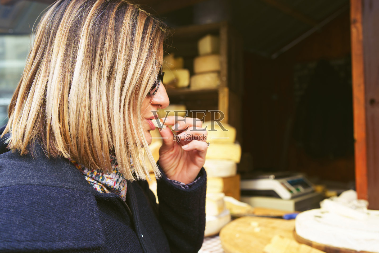 在欧洲或美国，白种人女性品尝和购买有机法国奶酪的街道市场在冬季或秋季的一天圣蜜糖或布里干酪照片摄影图片