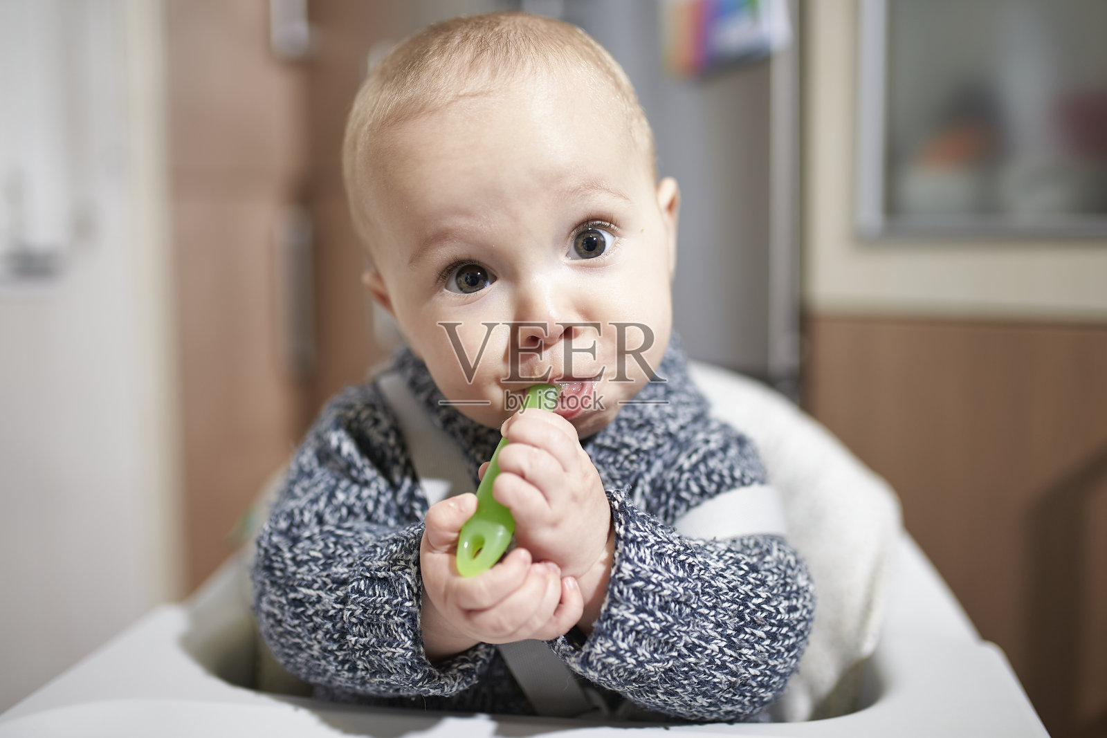 宝宝用勺子吃固体食物。BLW方法。照片摄影图片