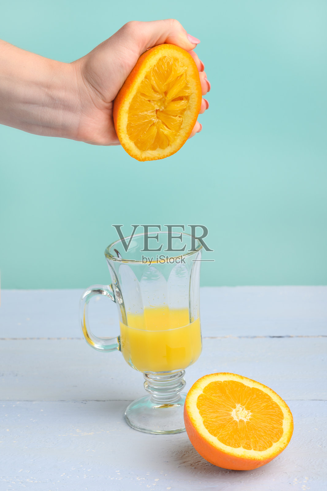 创意时尚的照片，色彩柔和。女用手捏碎橙汁。垂直的框架。美味的果汁和草莓的心情。照片摄影图片