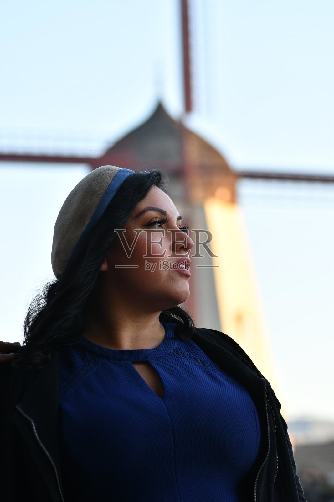 穿着蓝色裙子的年轻女子，风车在看别处照片摄影图片