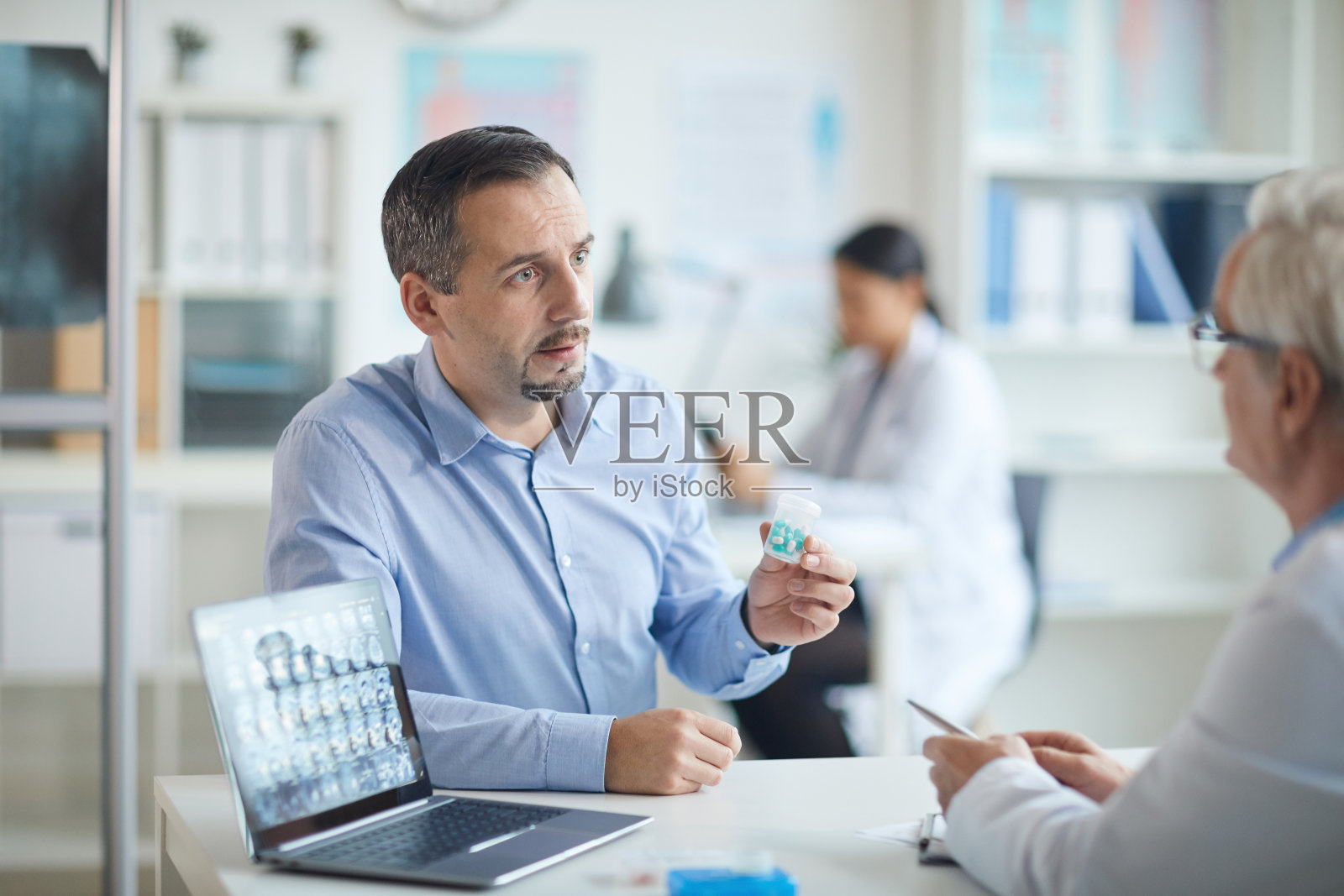 病人拿着药片和医生交谈照片摄影图片