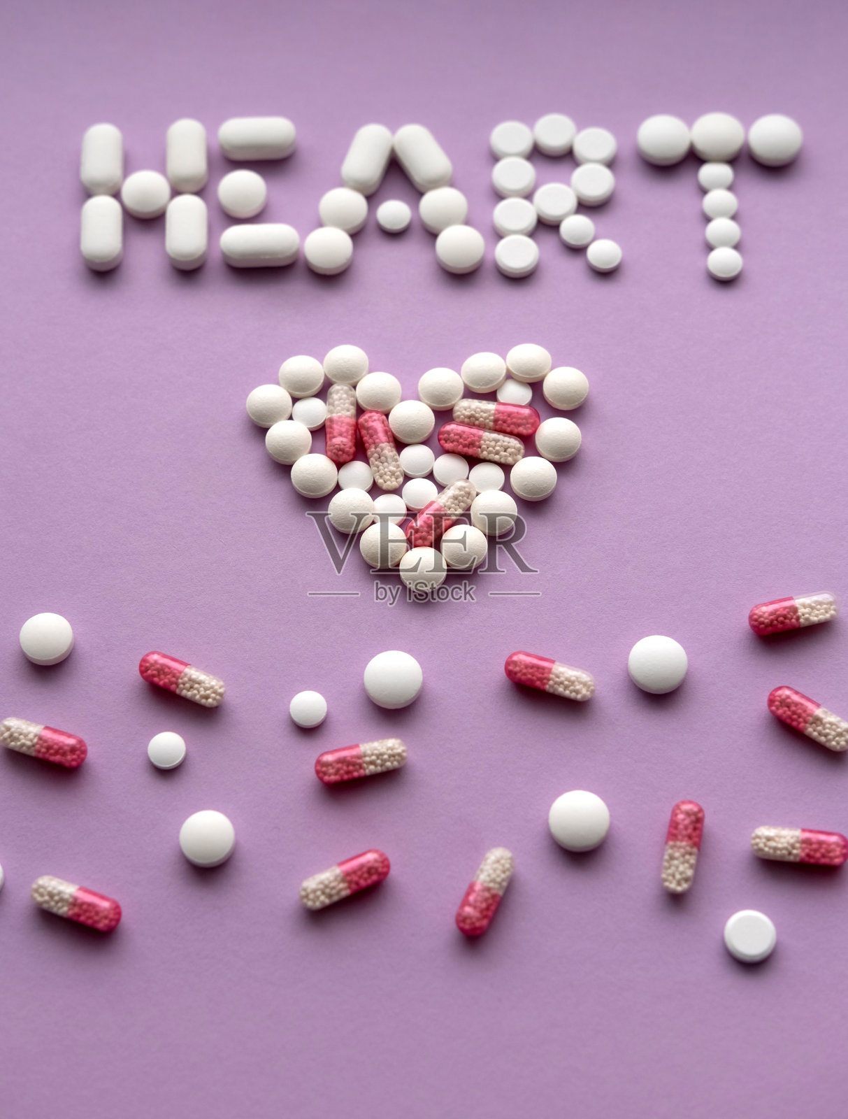 在粉彩背景上形成“心”字的各种药丸。彩色背景上的药片。前视图。医学概念。照片摄影图片