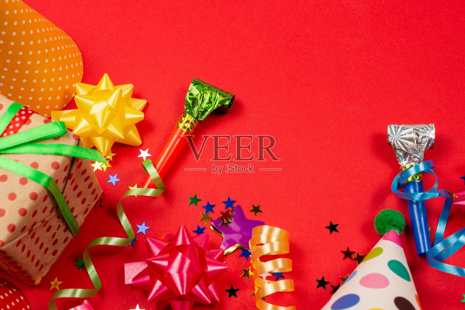 喜庆的金色和紫色星星五彩纸屑和礼物，红色背景上的生日帽。照片摄影图片