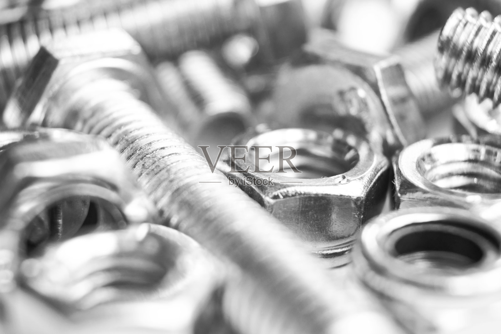 金属螺栓和螺母在一排背景。镀铬螺栓和螺母隔离。钢螺栓和螺母模式。一套螺母和螺栓。工作的工具。黑色和白色照片摄影图片