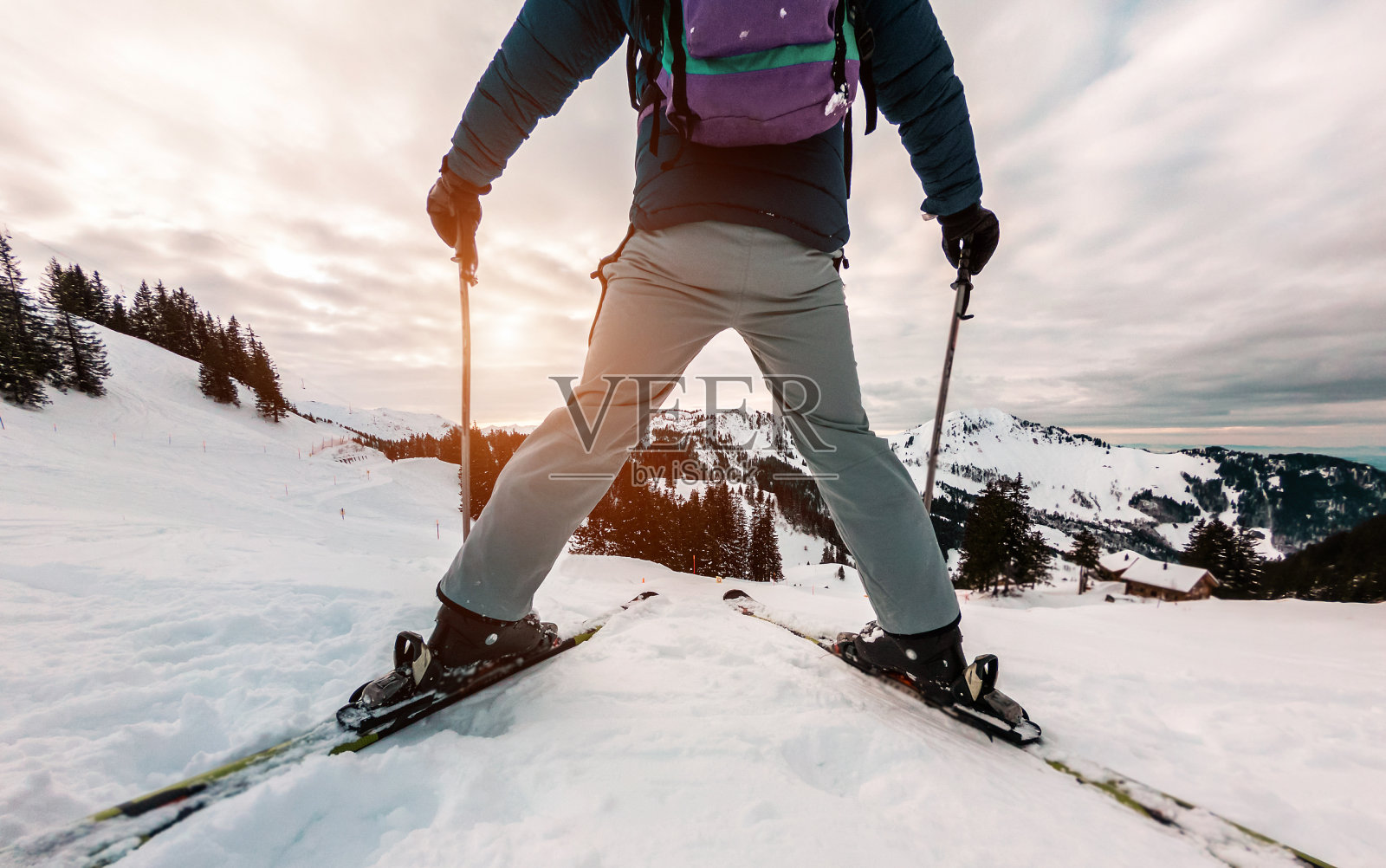 滑雪运动员站在山顶的日落前-腿的观点，年轻的滑雪者与太阳背光-运动和度假概念-柔软的焦点在男人的身体照片摄影图片
