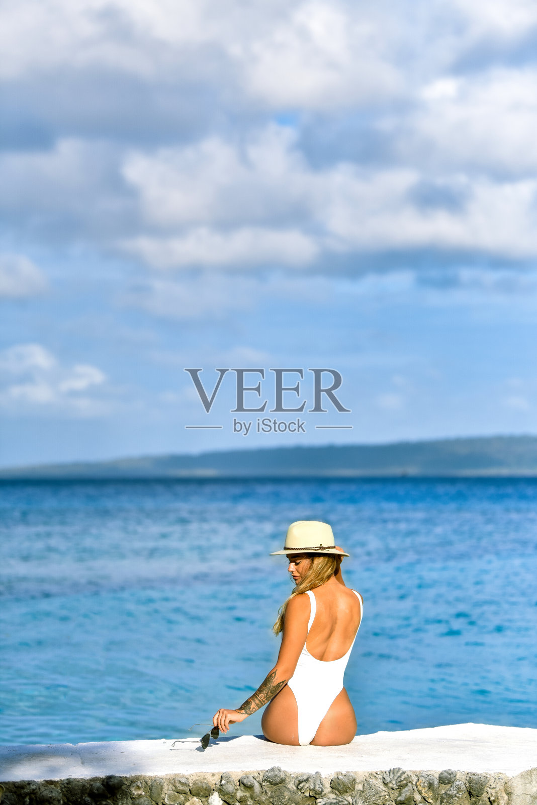 坐在海边的女人把太阳镜放在一边照片摄影图片