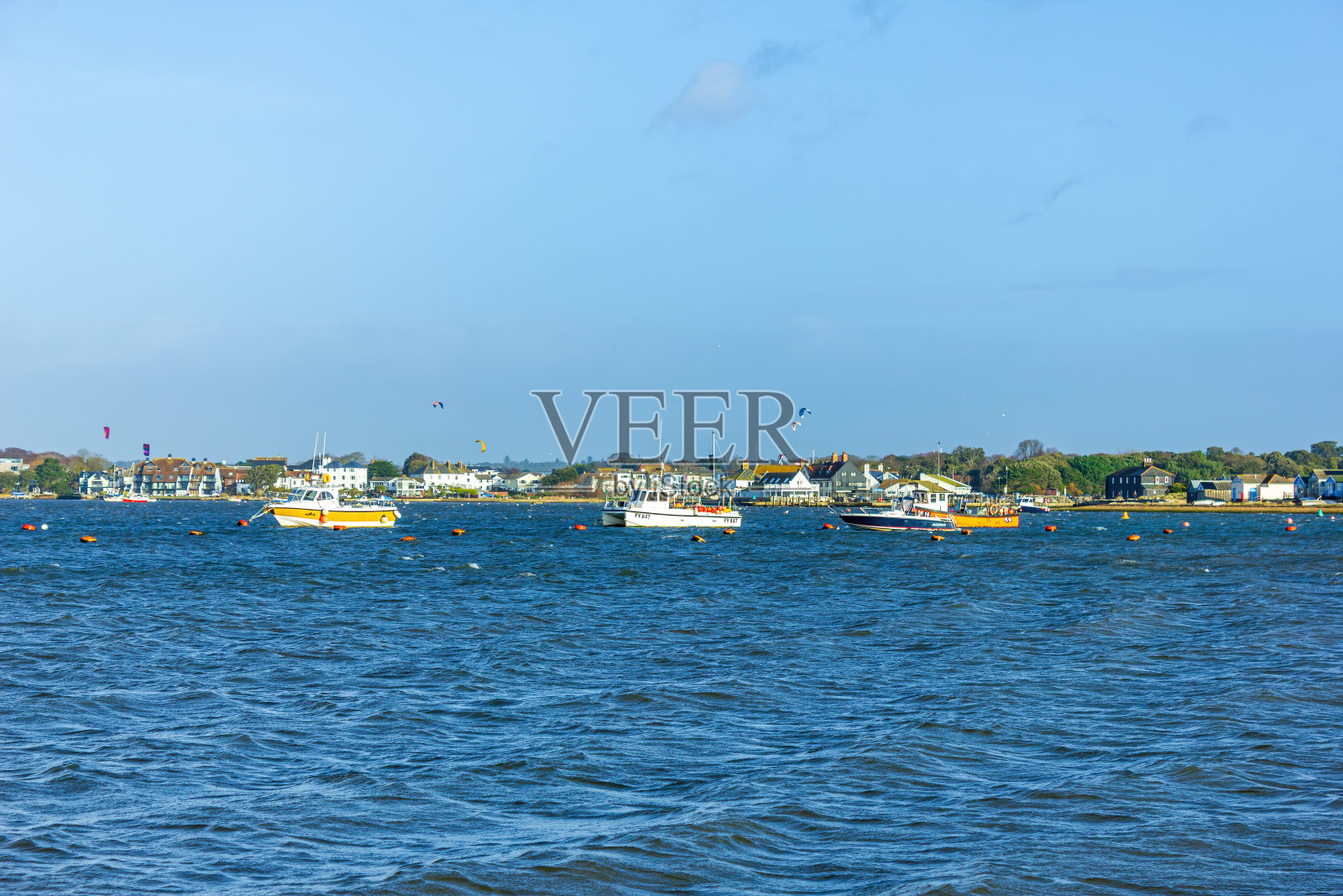 克赖斯特彻奇(英国)港口的近景，前景和风筝冲浪者，房子在宏伟的蓝天和一些白云的背景下照片摄影图片