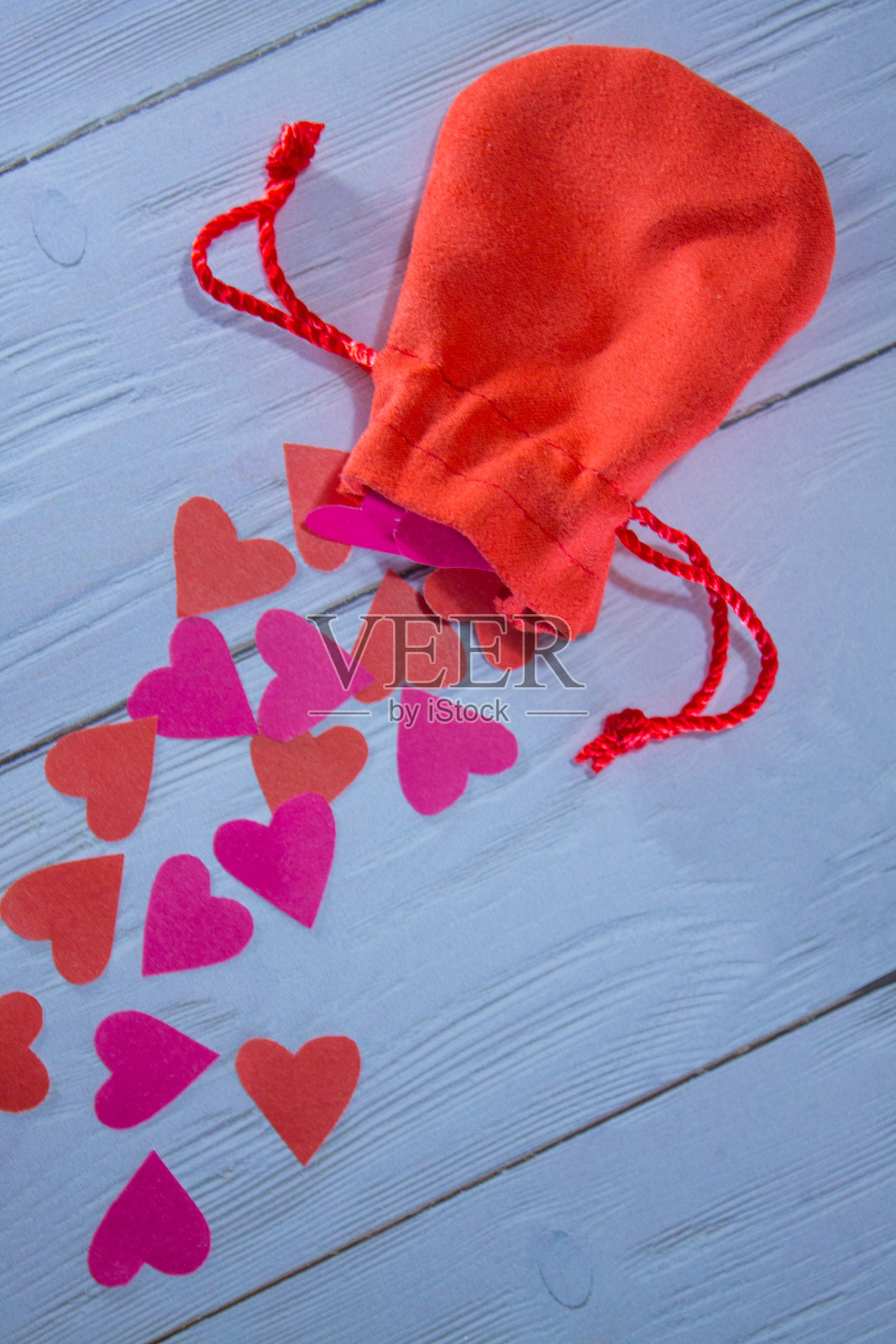 白色木质表面上散落着一颗心的红色袋子照片摄影图片